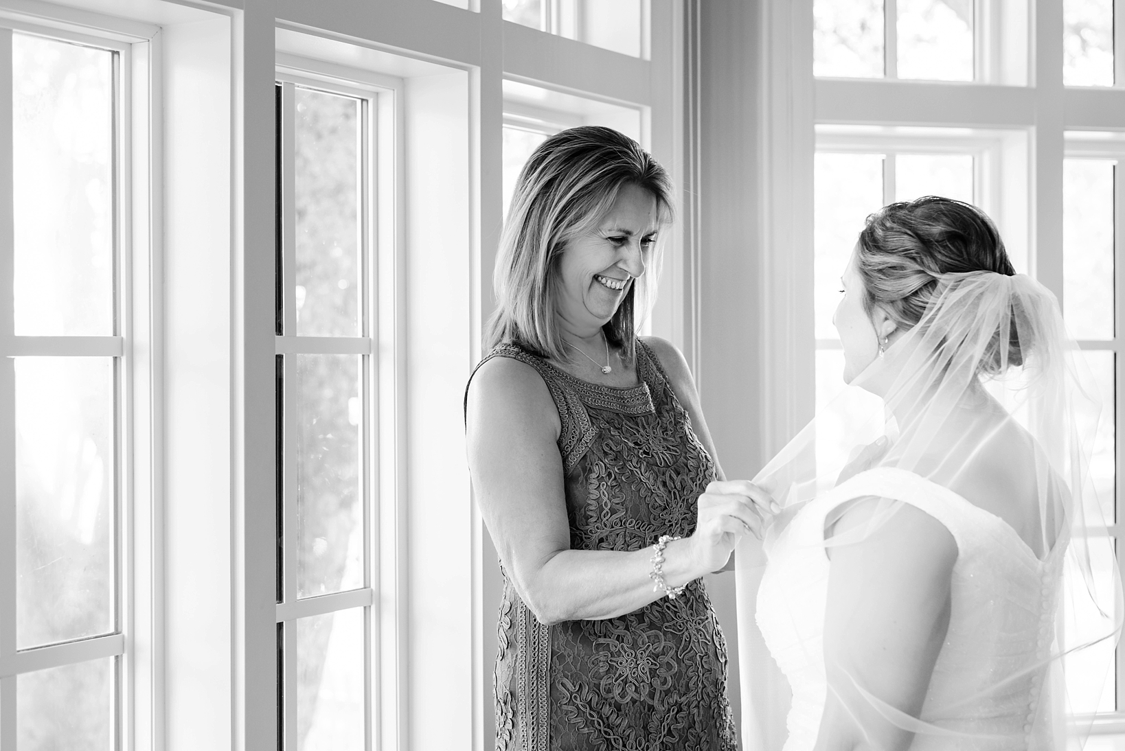 The Bride's mother assists with putting the veil on her daughter before her wedding
