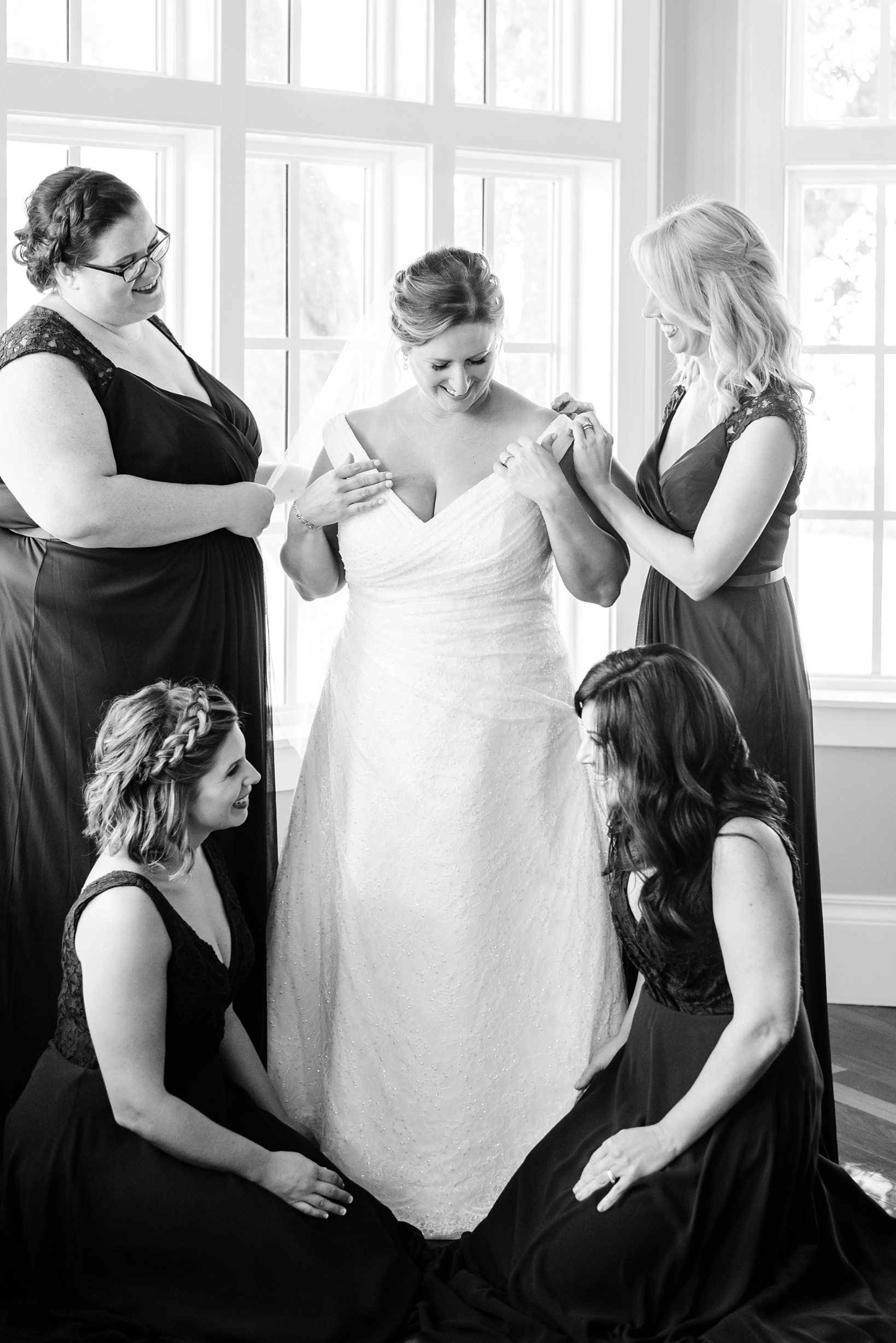 Classic image of a bride and her bridesmaids helping get her ready for the wedding