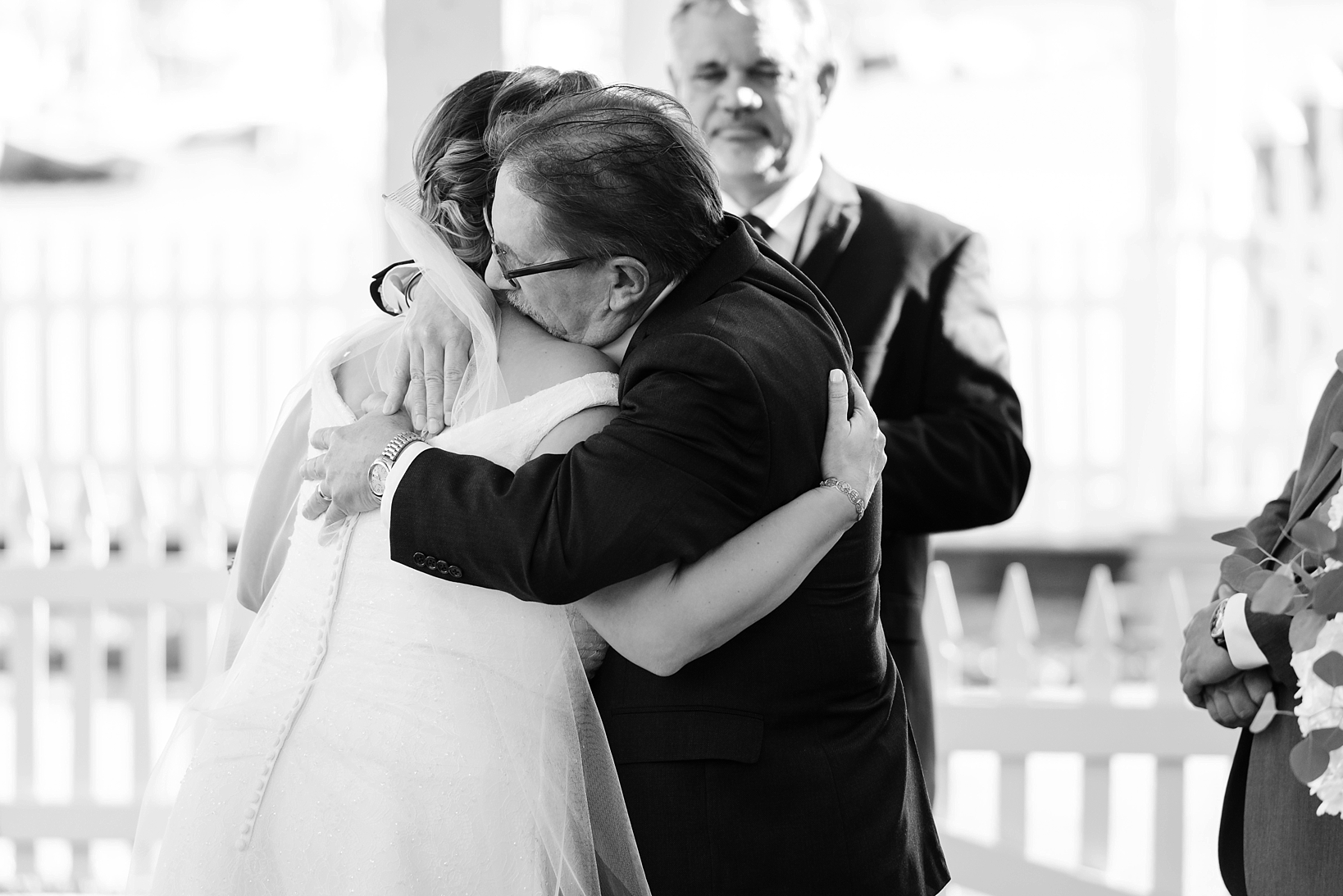 Father hugs his daughter during the wedding ceremony in black and white