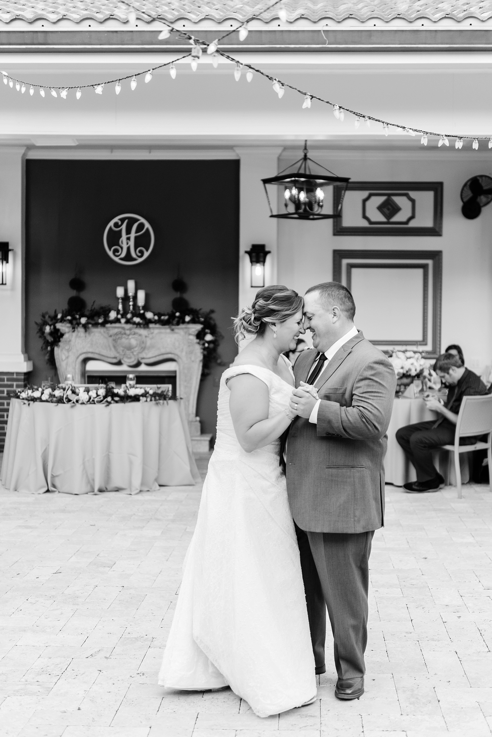 The couple share a smile during their first dance under the string lights