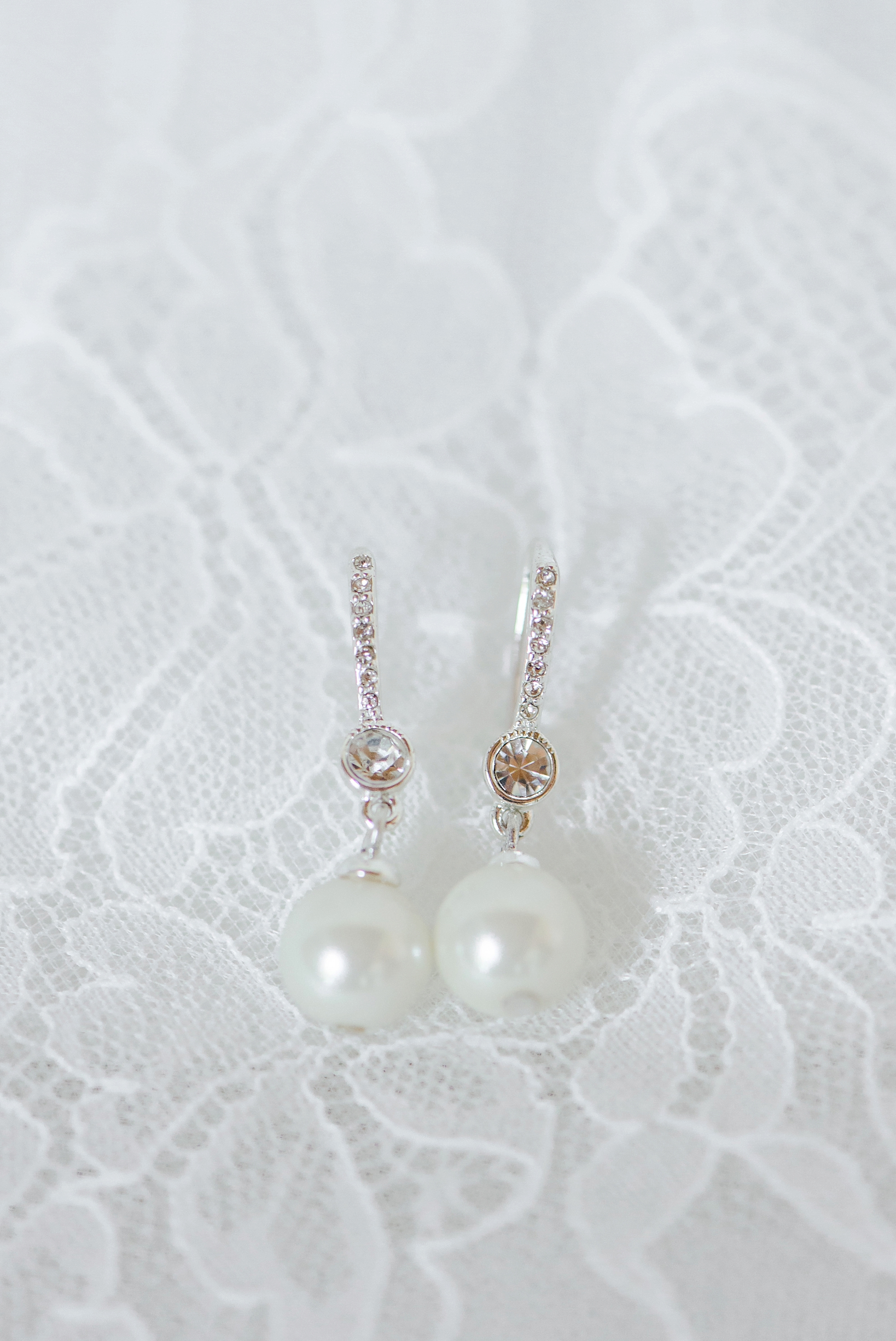 Bride's pearl earrings on white lace