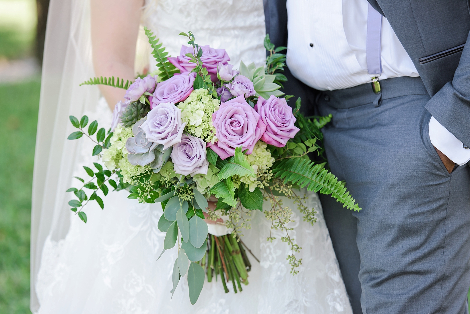 Bride holding her bouquet and grooms lavender suspenders