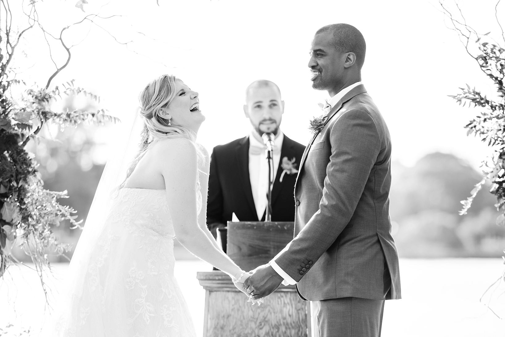 Black and White image of a bride laughing during the ceremony