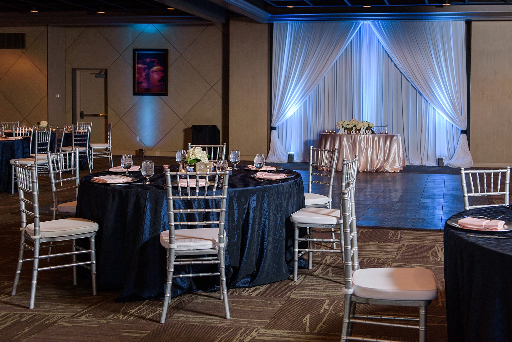 Reception space with blue uplighting along the drapes and chivari chairs