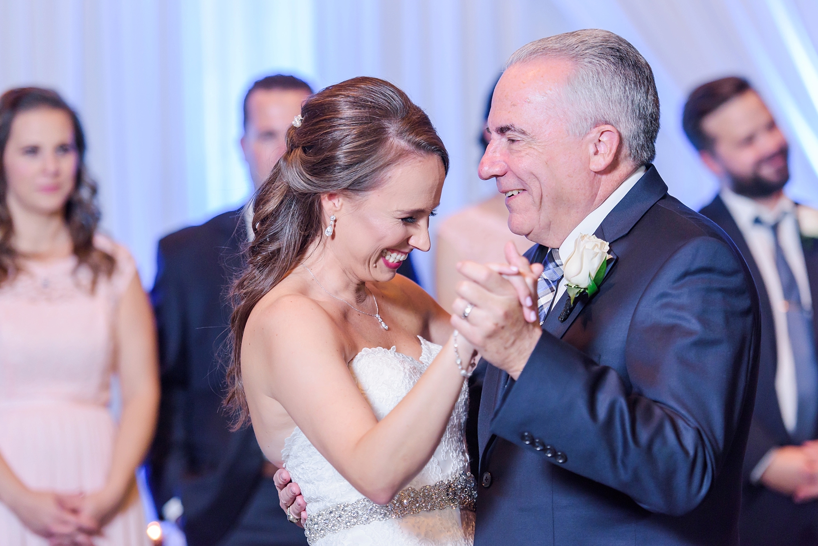 Bride shares a laugh during the Father/Daughter dance with the Bridal Party looking on by Sarah & Ben Photography