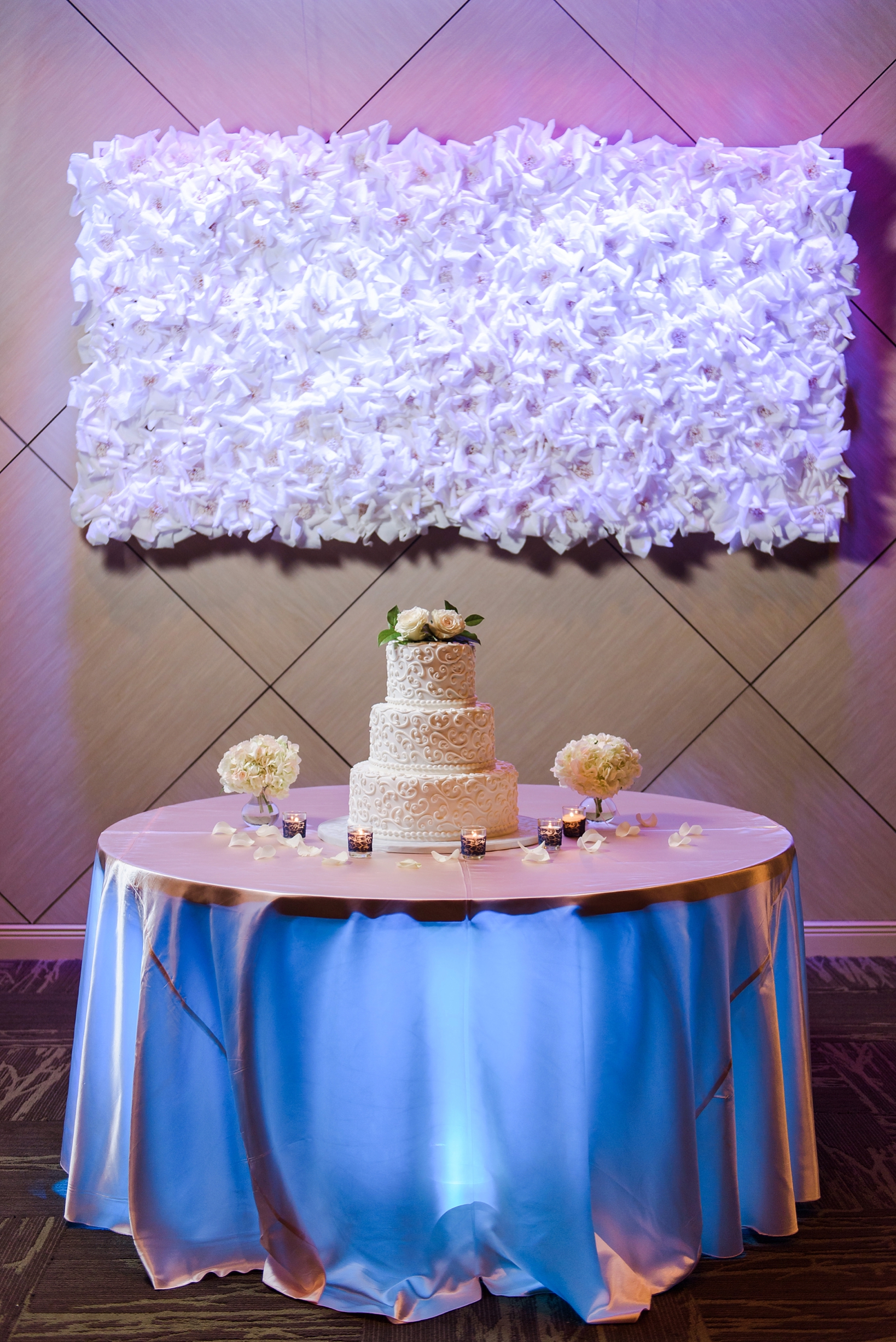 The cake table being uplight by purple and blue lights