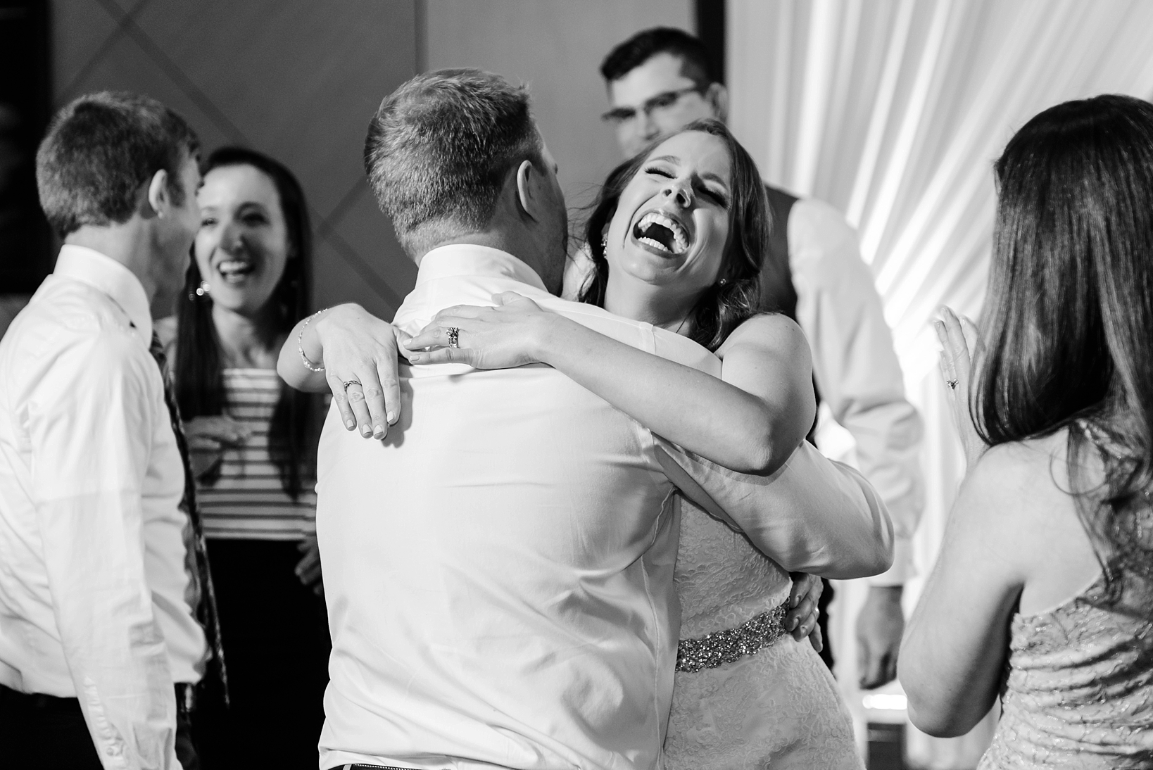 Bride laughing while dancing with her wedding guests on the dance floor by Sarah & Ben Photography