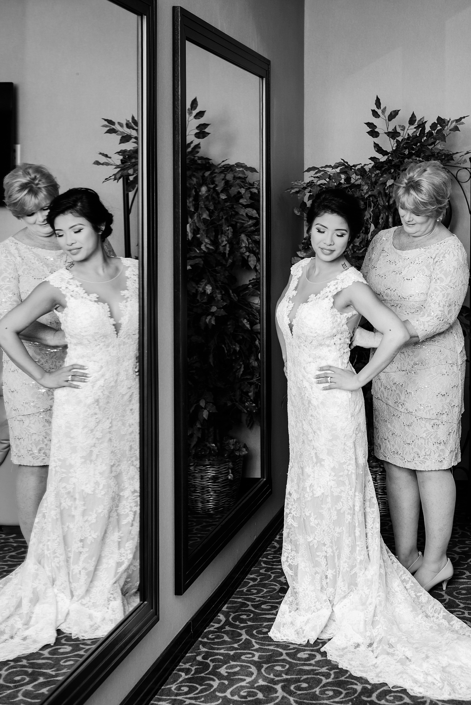 Black and white image of the bride getting into her dress in front of a mirror