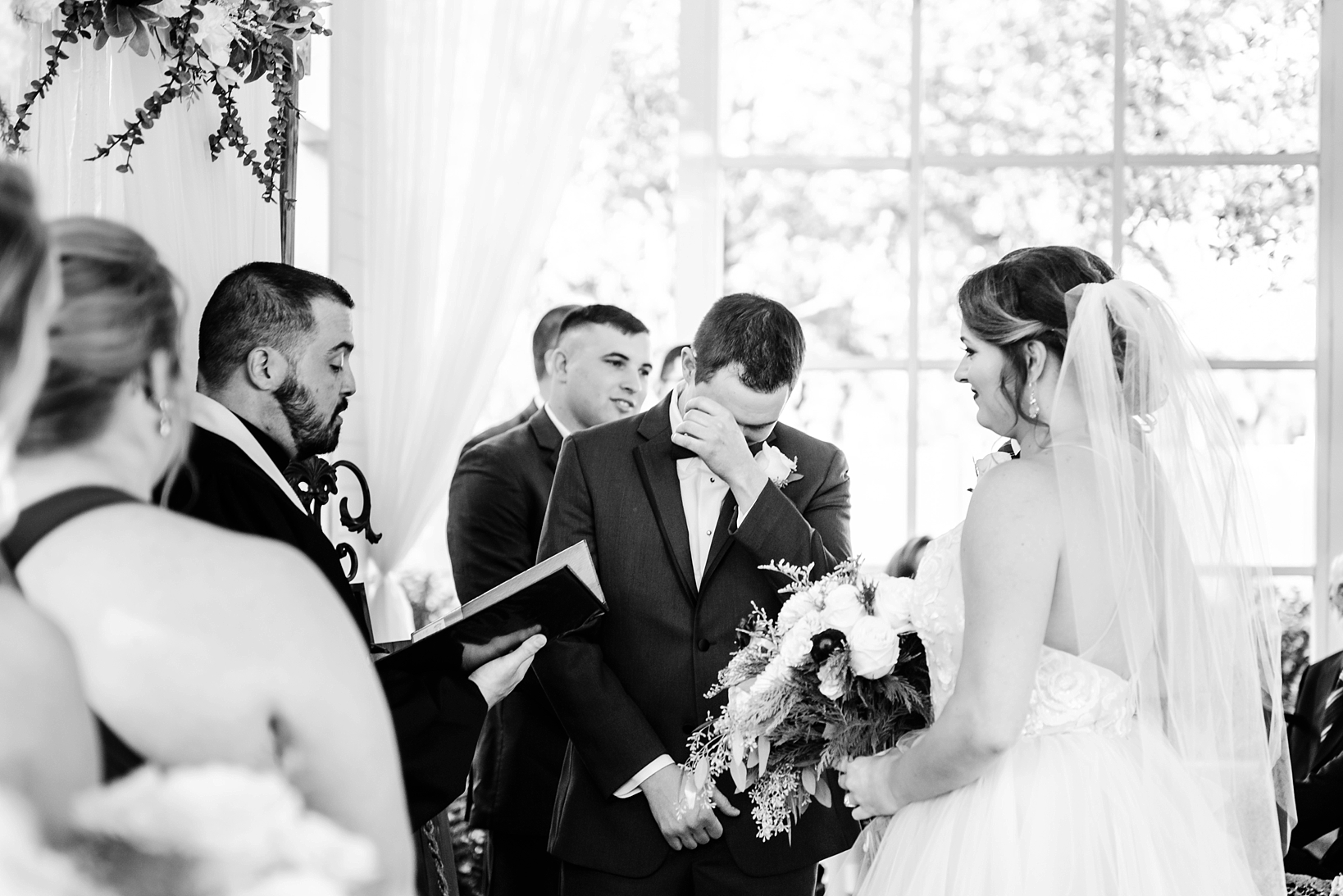 Groom wiping his tears away from his eyes during the wedding ceremony while seeing his bride for the first time