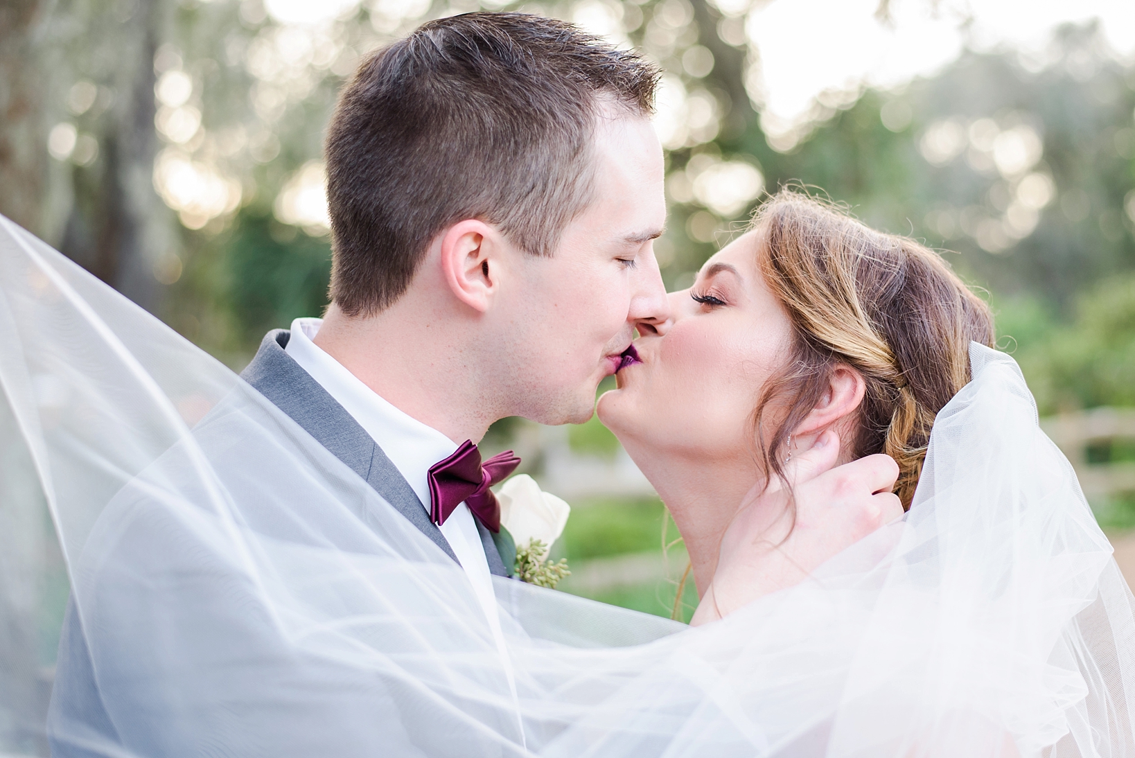 A kissing Bride and Groom surrounded by the cathedral veil