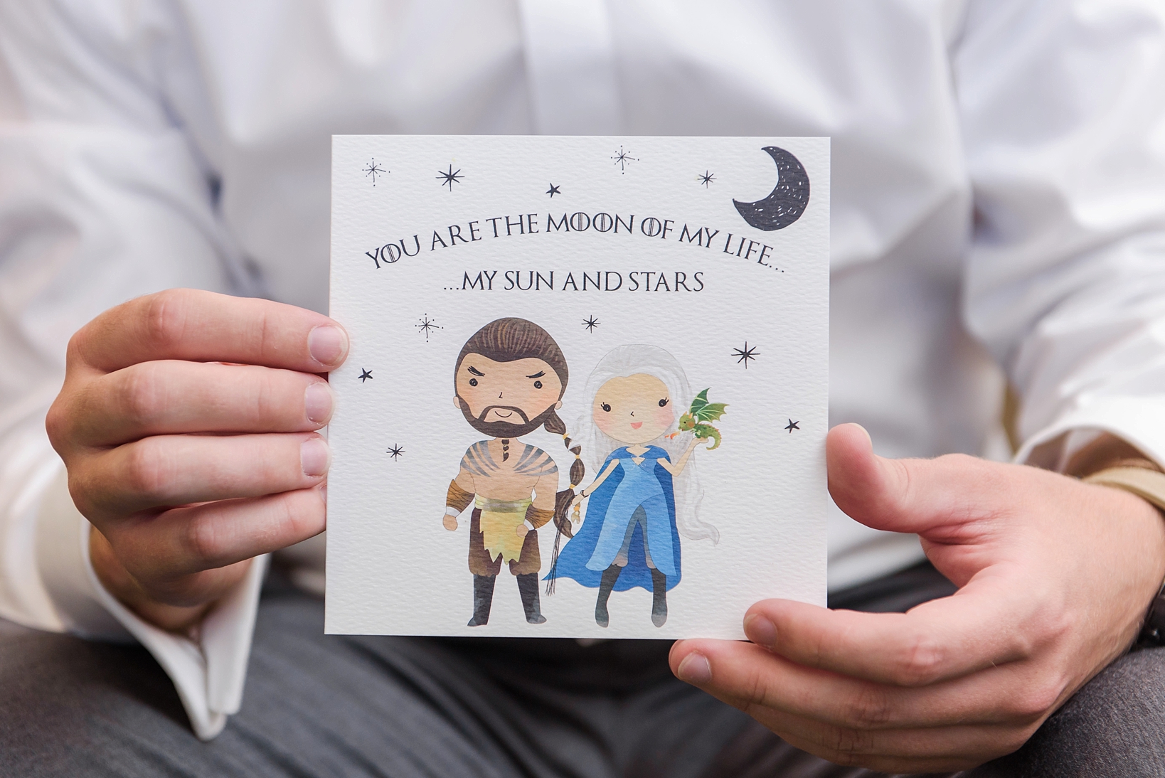 Groom holding up his Game of Thrones inspired wedding card given to him by his Bride
