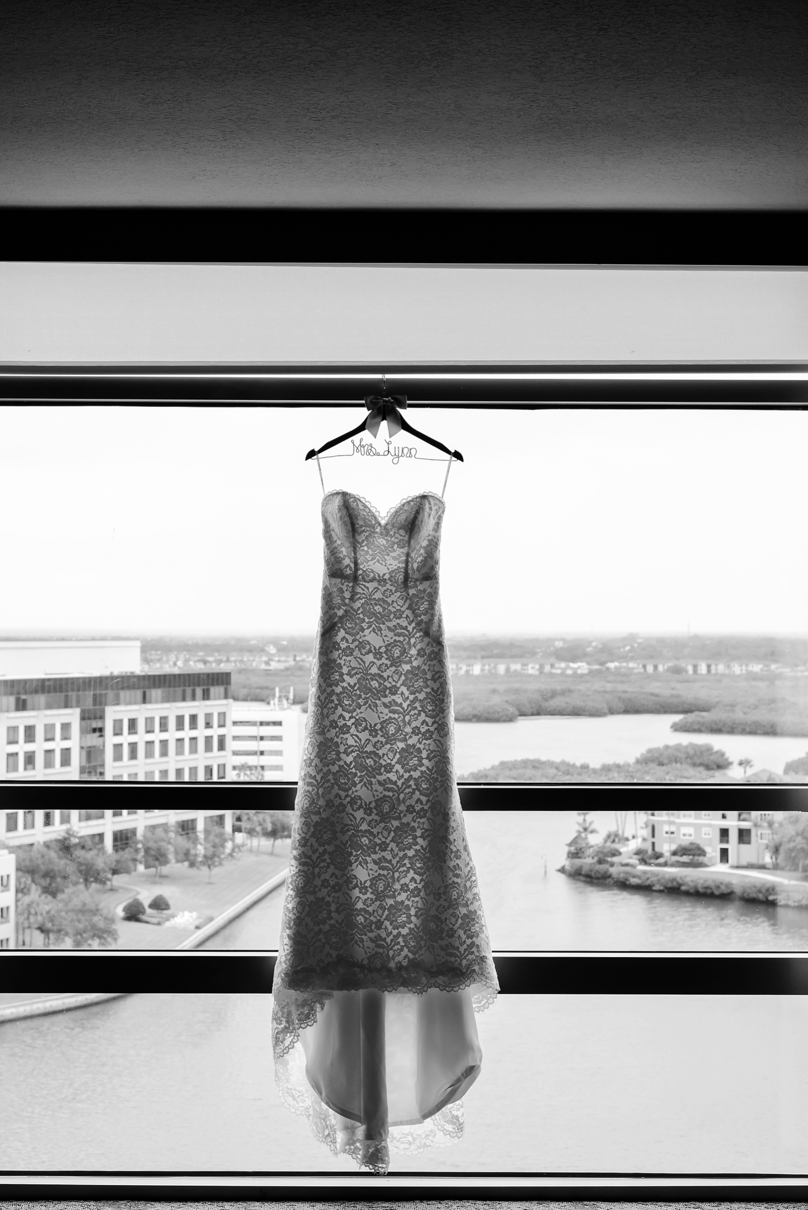 Black and White image Bridal Gown hanging in a window