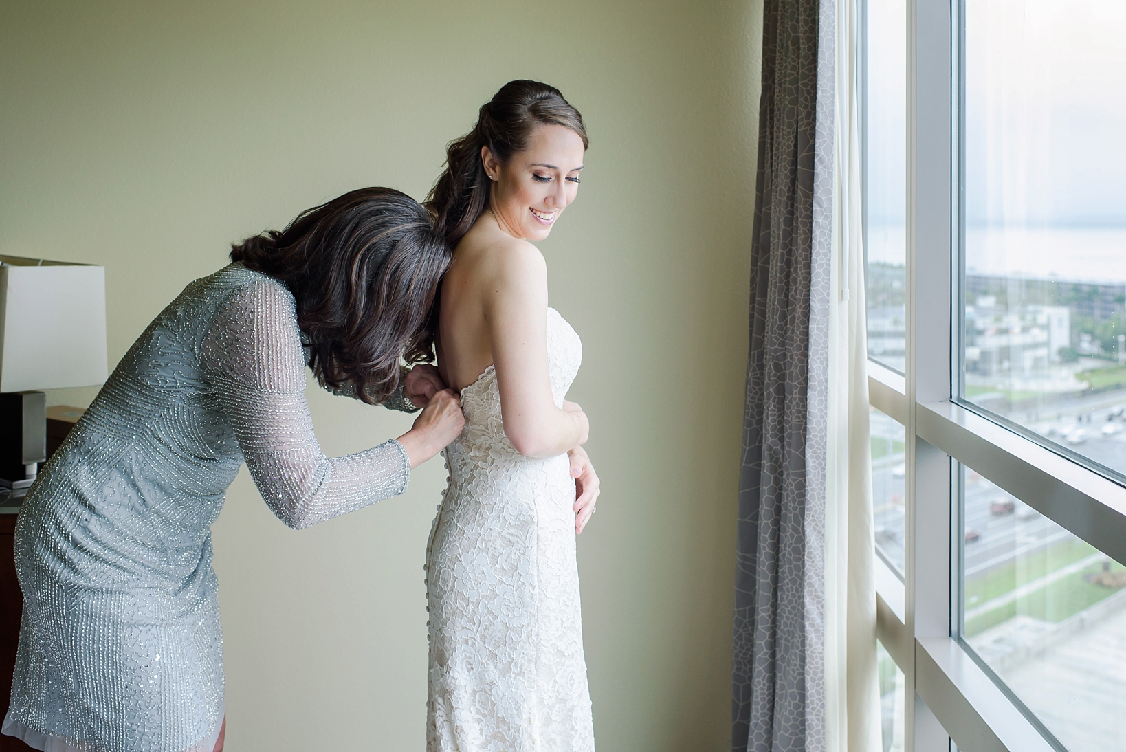 Mom helping her daughter into her wedding gown in Tampa, FL by Sarah & Ben Photography