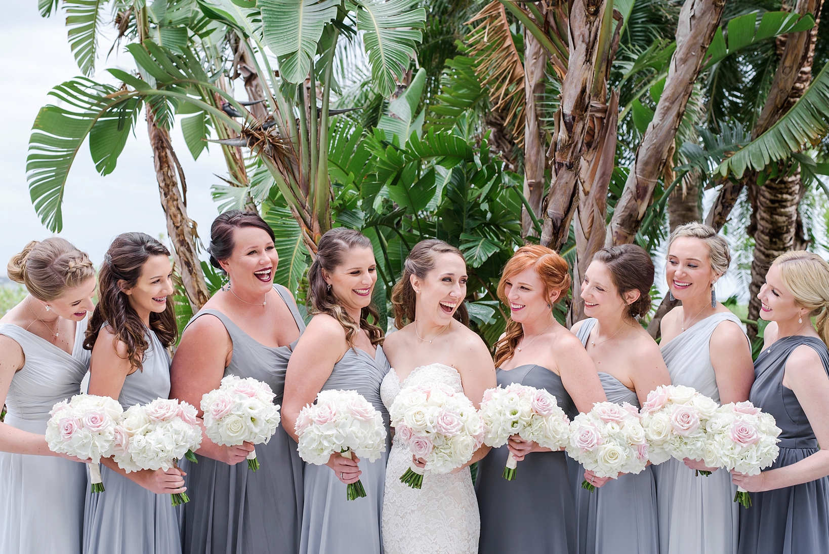Bride and her Bridesmaids laughing together while holding their bouquets