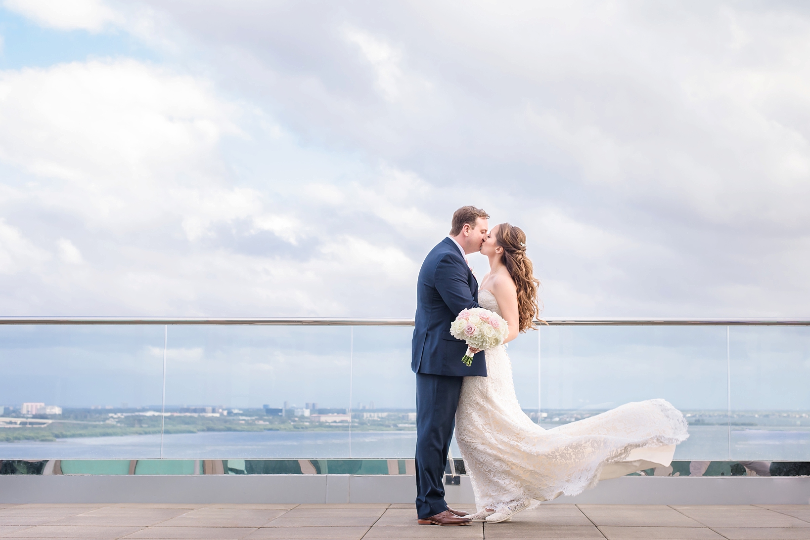 Bride and Groom kiss while the wind blows the dress