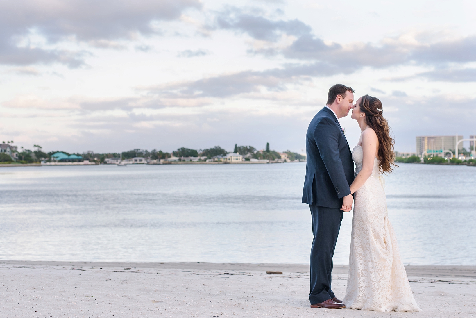 Bride and Groom kissing on a cloudy beach afternoon by Sarah & Ben Photography