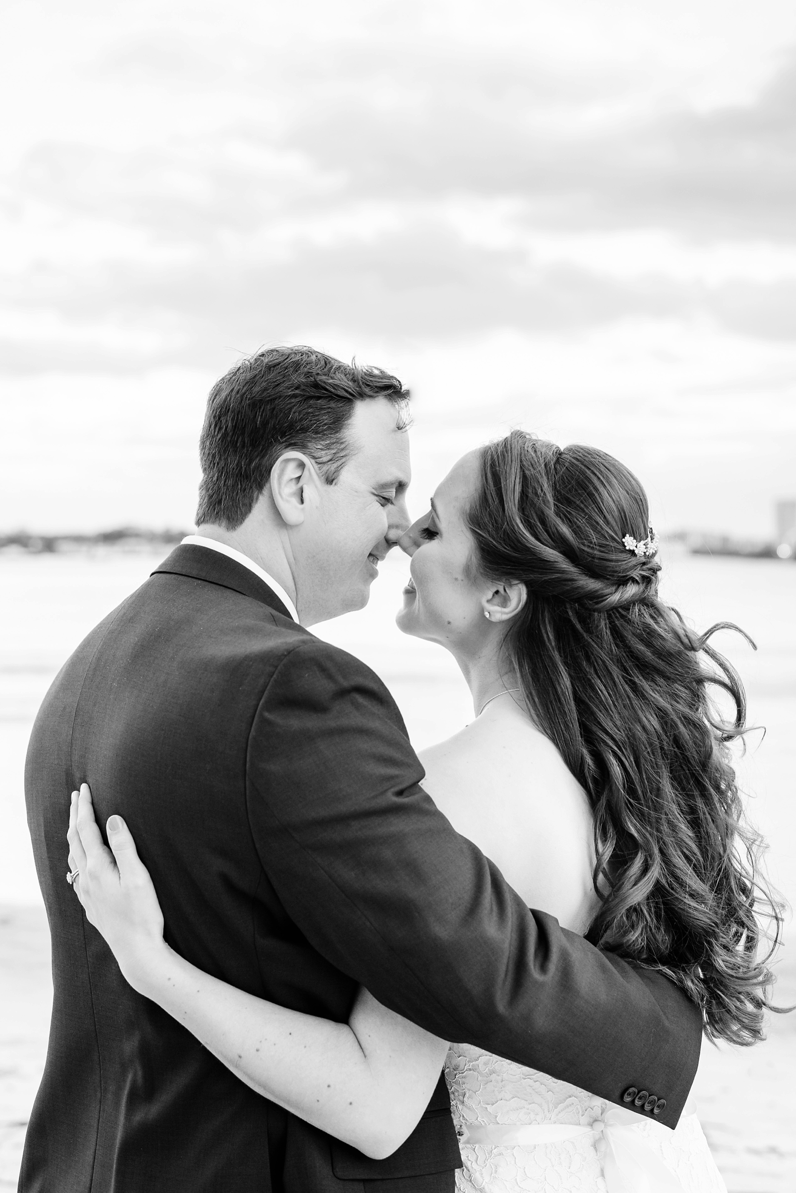 Black and white image of the couple smiling as they kiss
