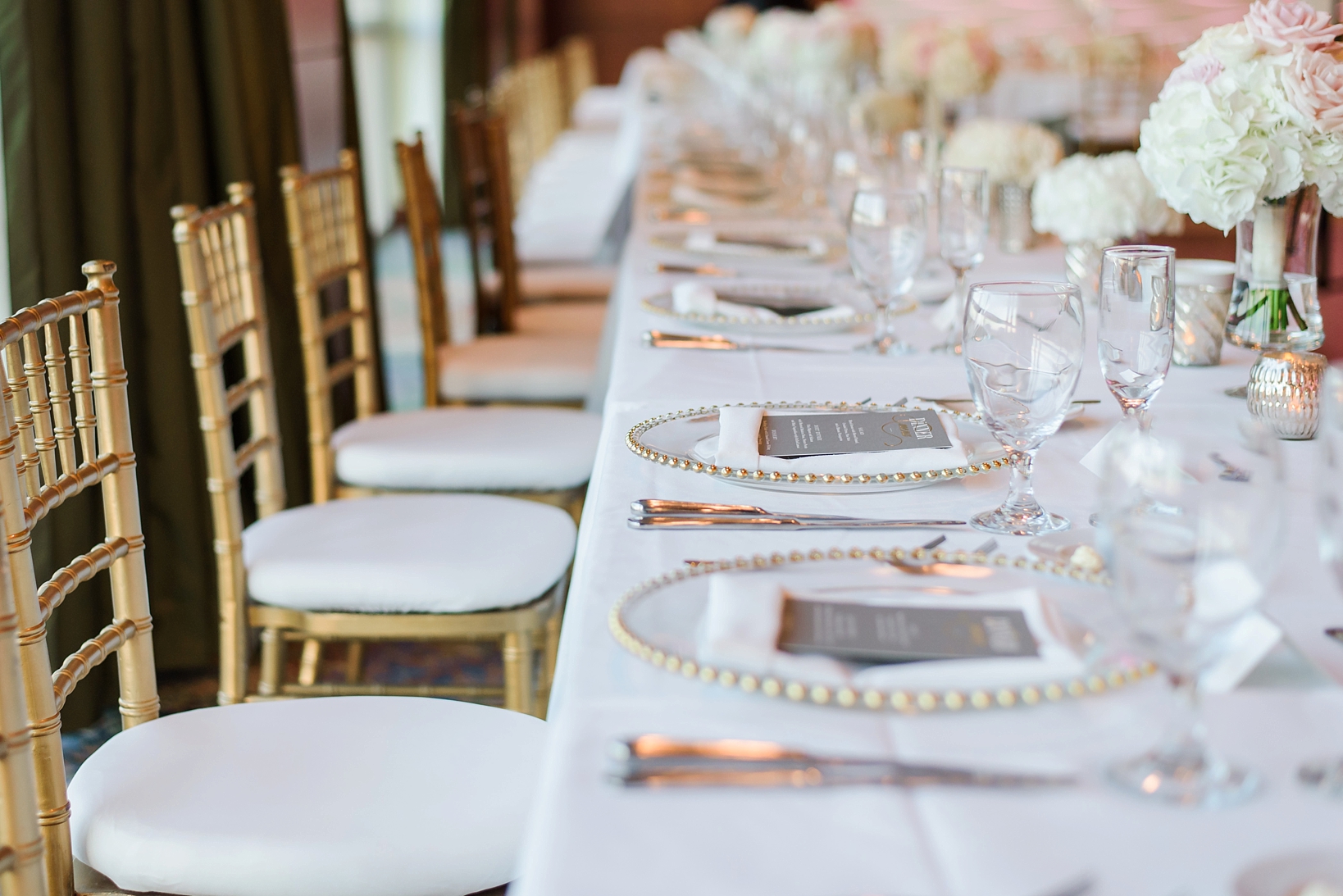 Long head table with gold accents and chargers and chiavari chairs by Sarah & Ben Photography