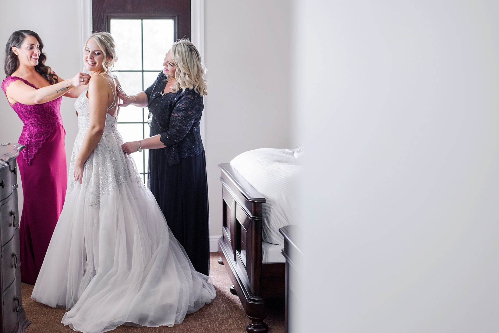 Bride being helped into her Hayley Paige gown by her Mother and Maid of Honor