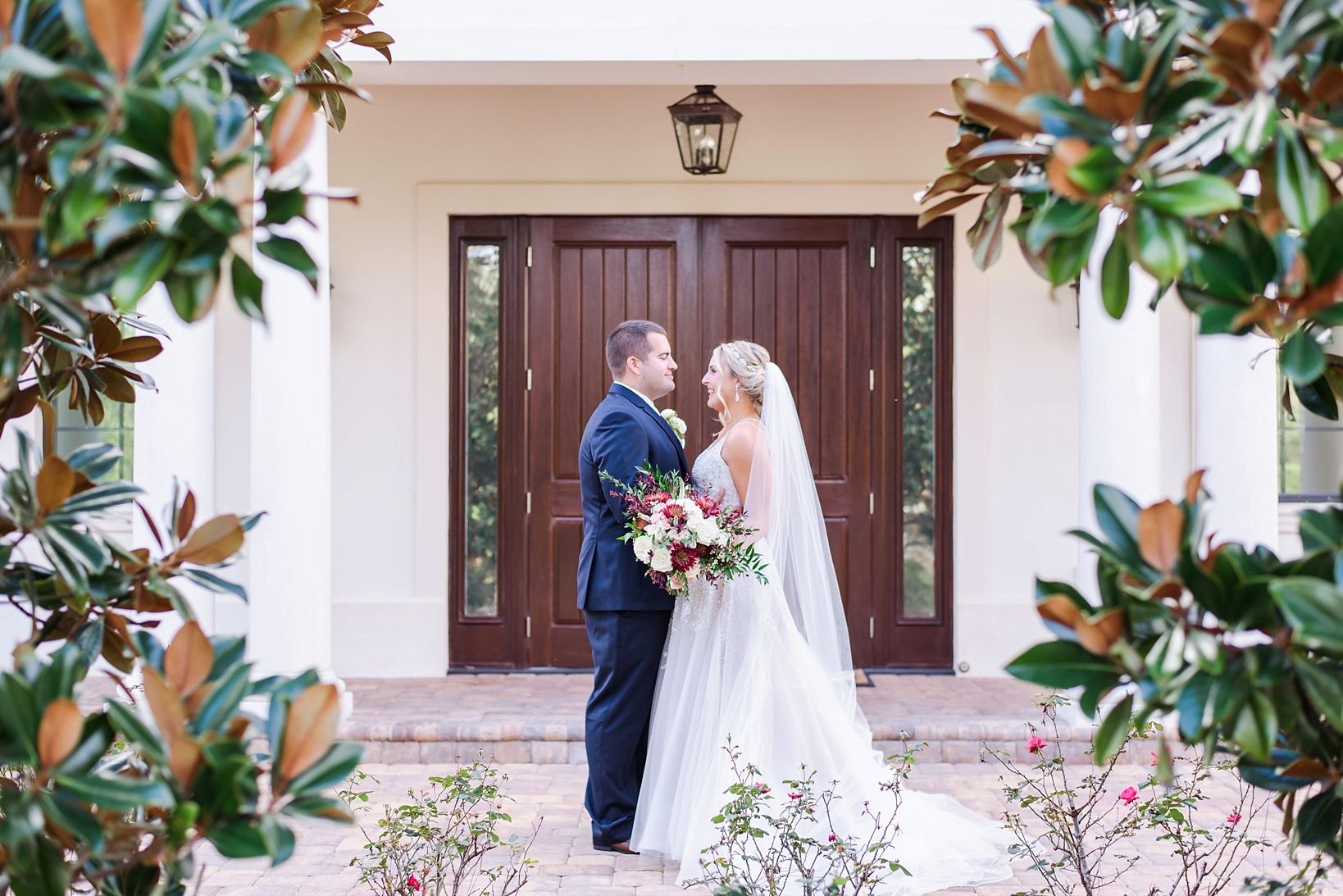 Bride and groom against a dark wood doorway framed by trees