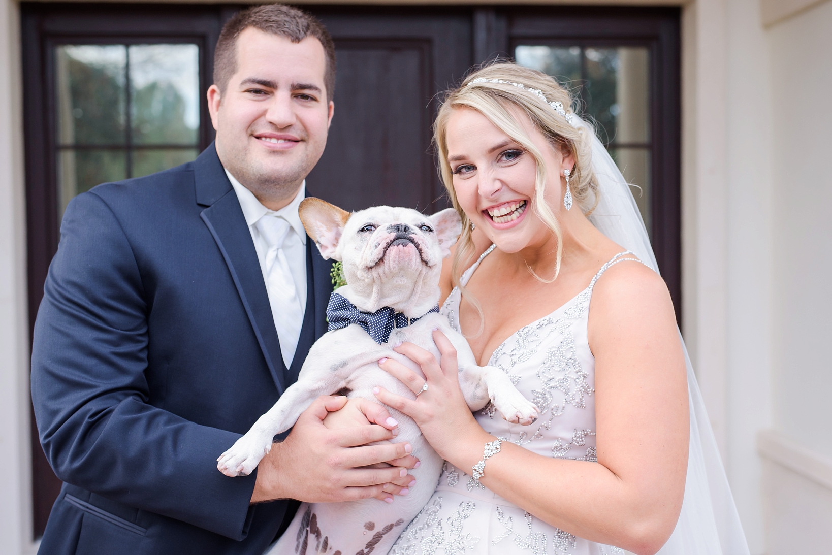 Bride and Groom holding their French Bulldog in a bow tie