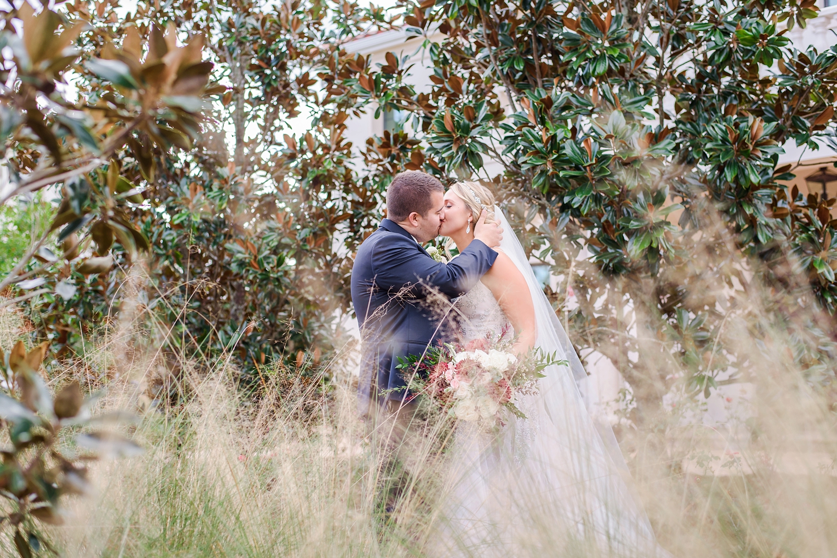 Bride and Groom kissing among the trees and tall grass