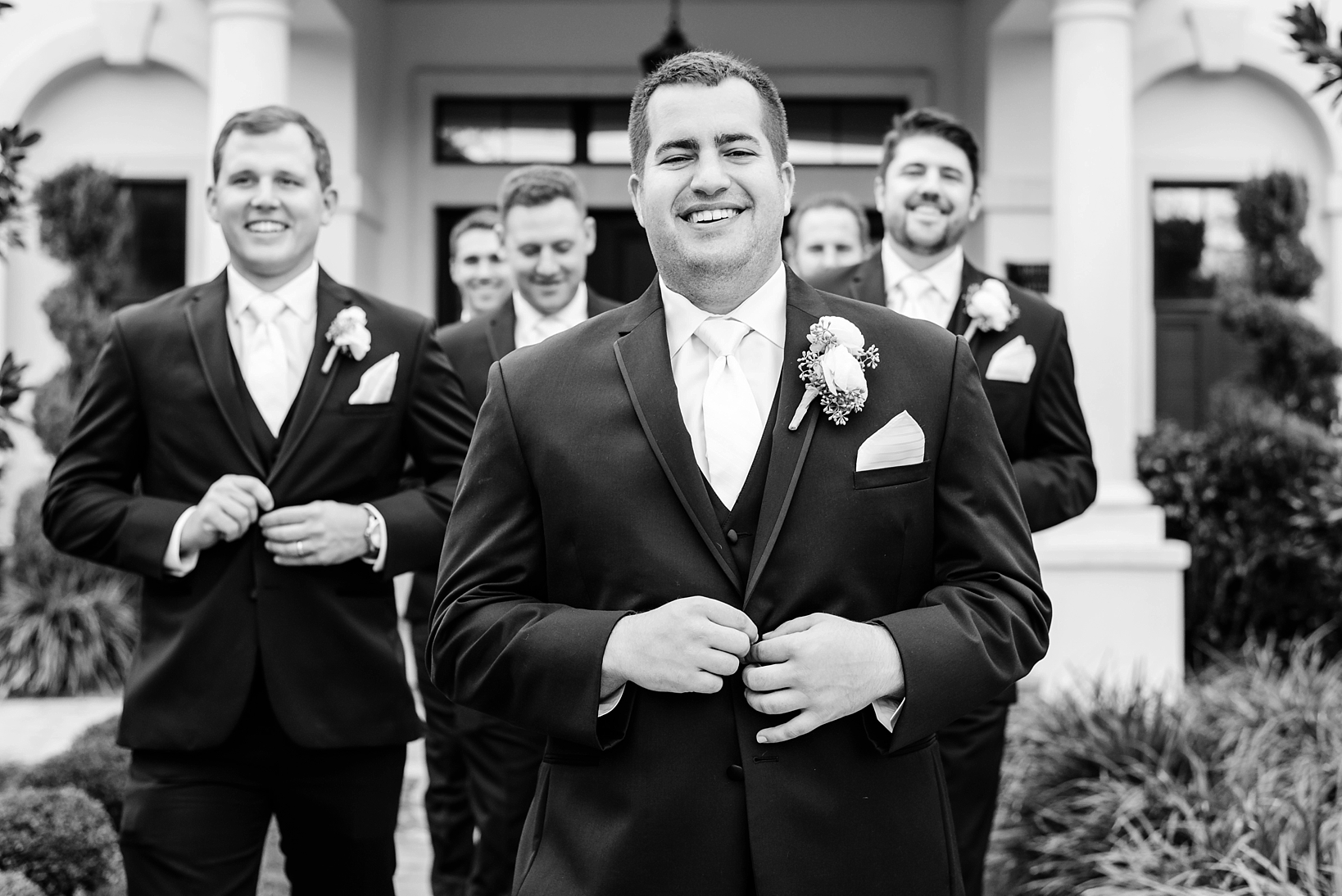Groom followed by his Groomsmen in black and white walking toward the camera