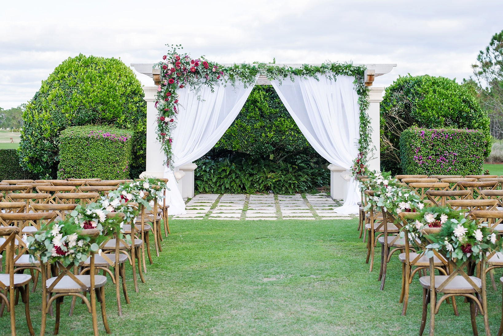 Beautiful flower arch at the end of a rustic filled decorated wedding aisle
