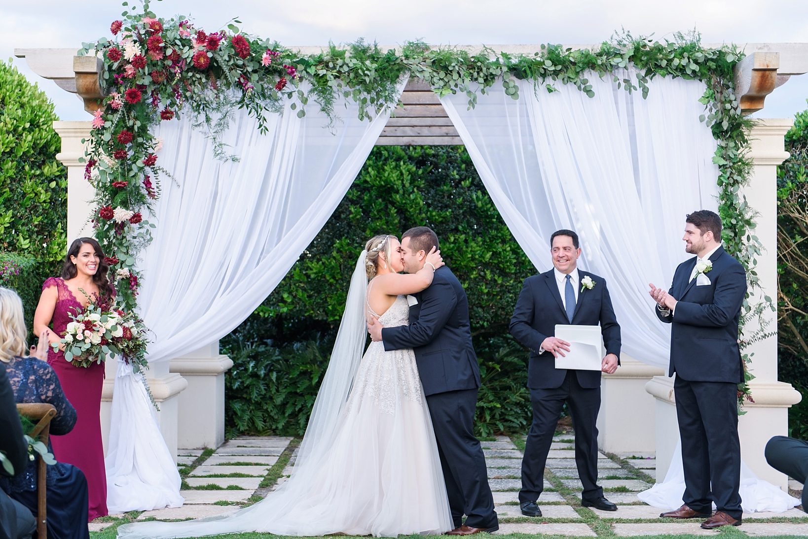 The first kiss as Mr. & Mrs. under a floral arch