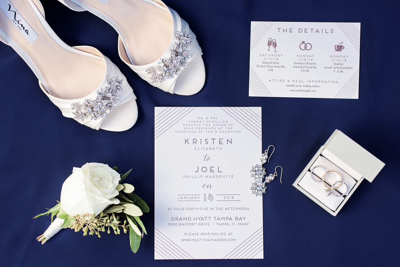 Lay flat of wedding jewelry and florals with navy color tones