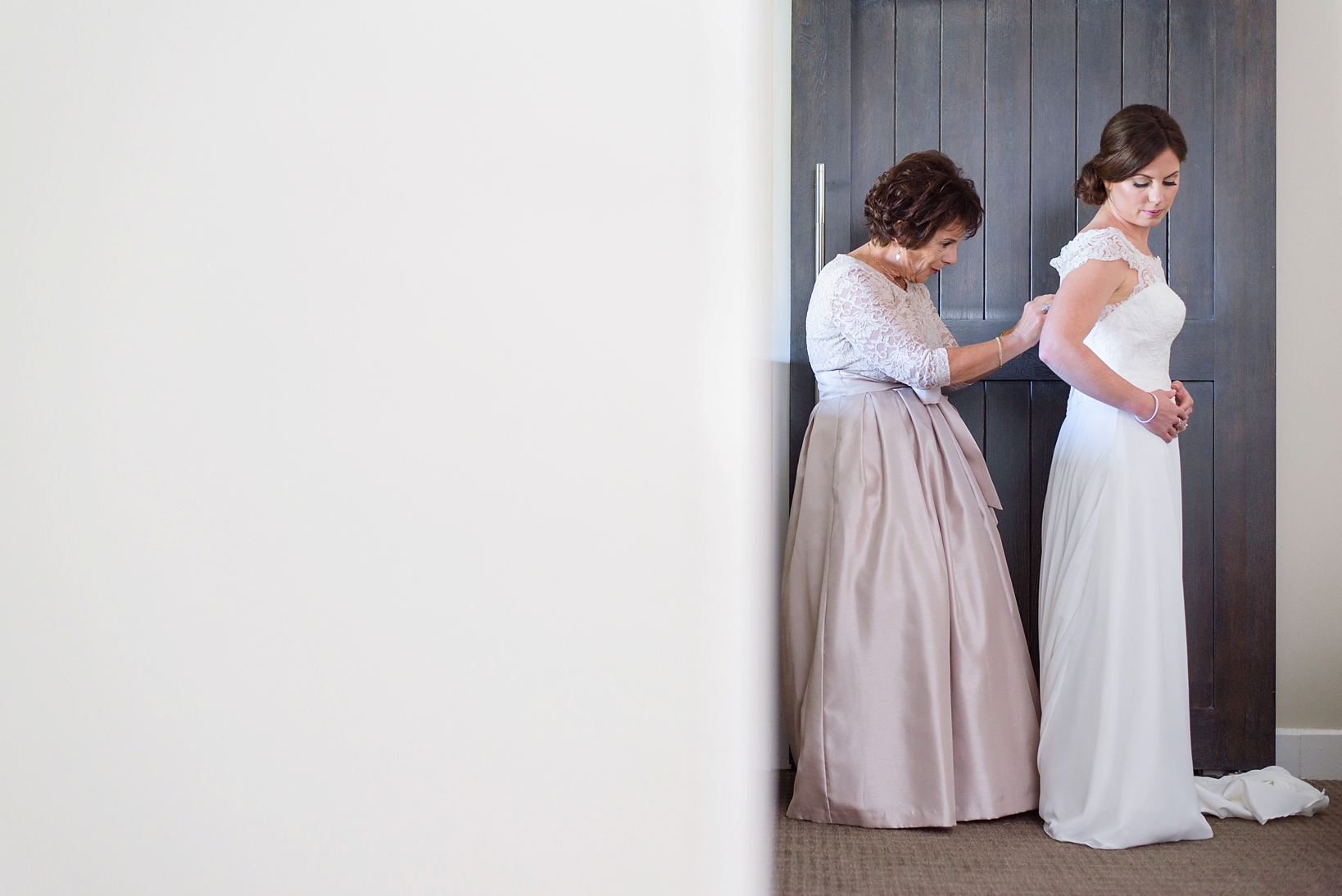 Bride being helped into her dress by her mother