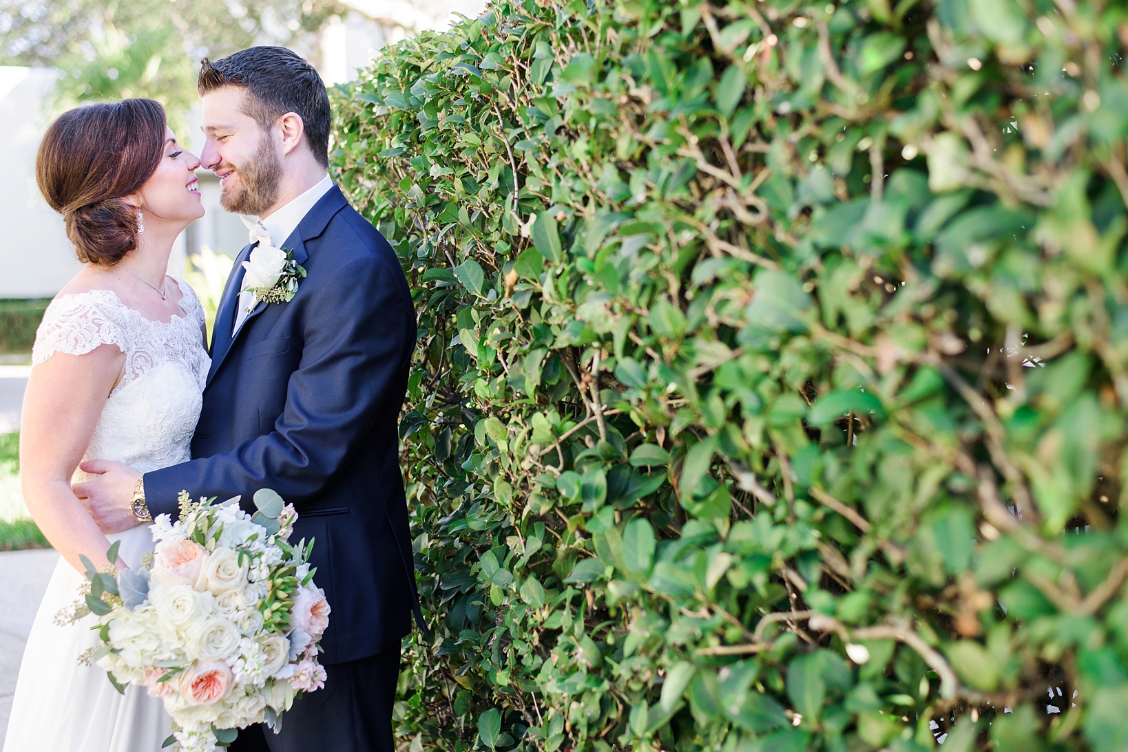 Bride and Groom leaning against a hedge
