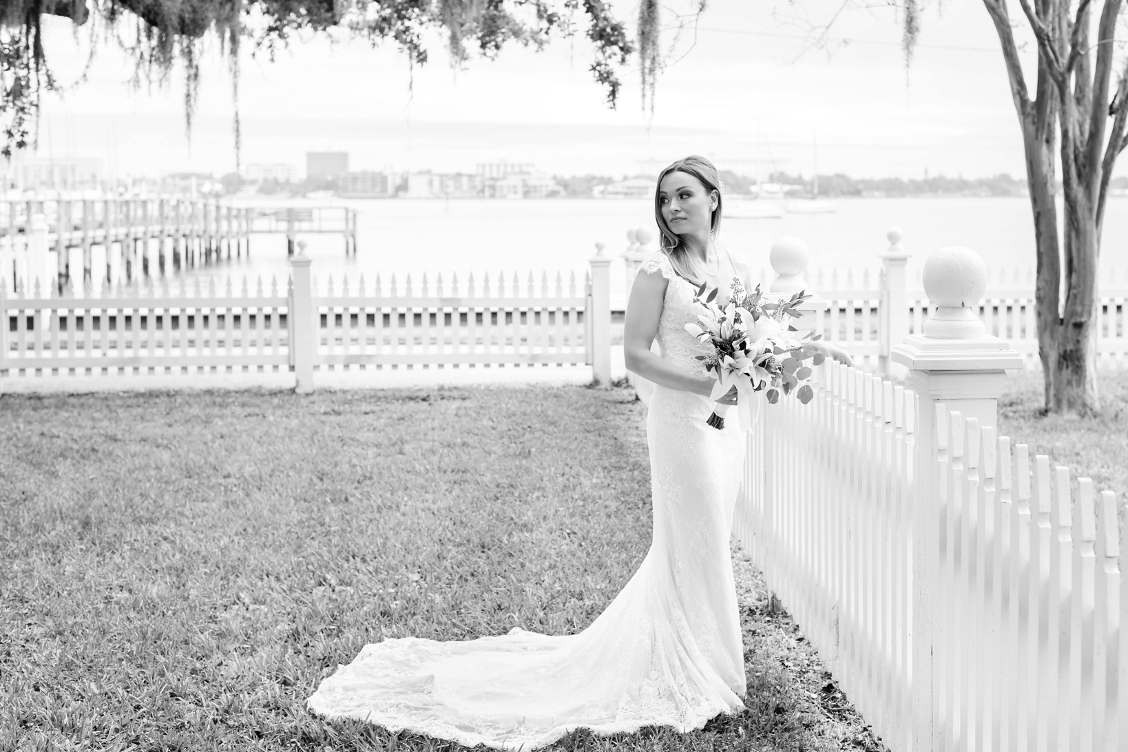 Black and White of the Bride holding her bouquet against a white picket fence