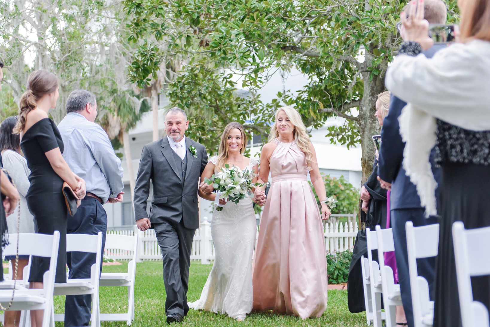 Bride walking down the aisle with her mom and dad by Sarah & Ben Photography
