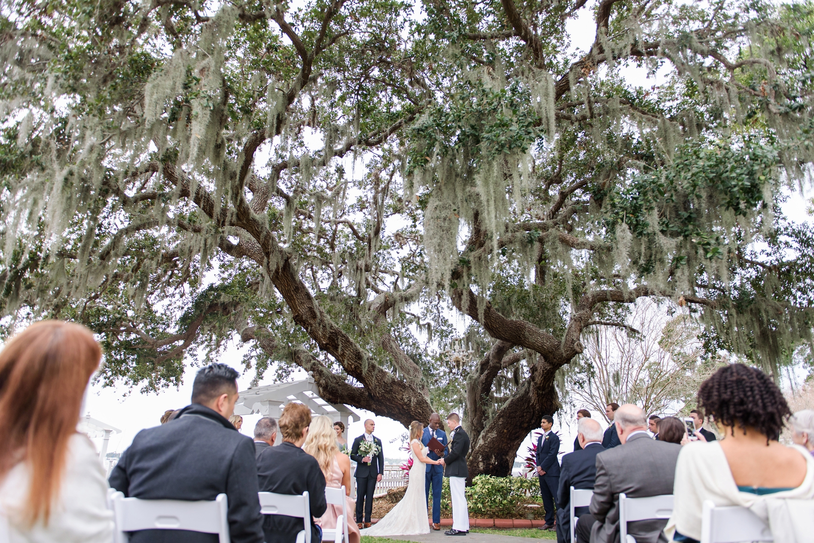 Bride and Groom standing under the oak tree during their ceremony by Sarah & Ben Photography