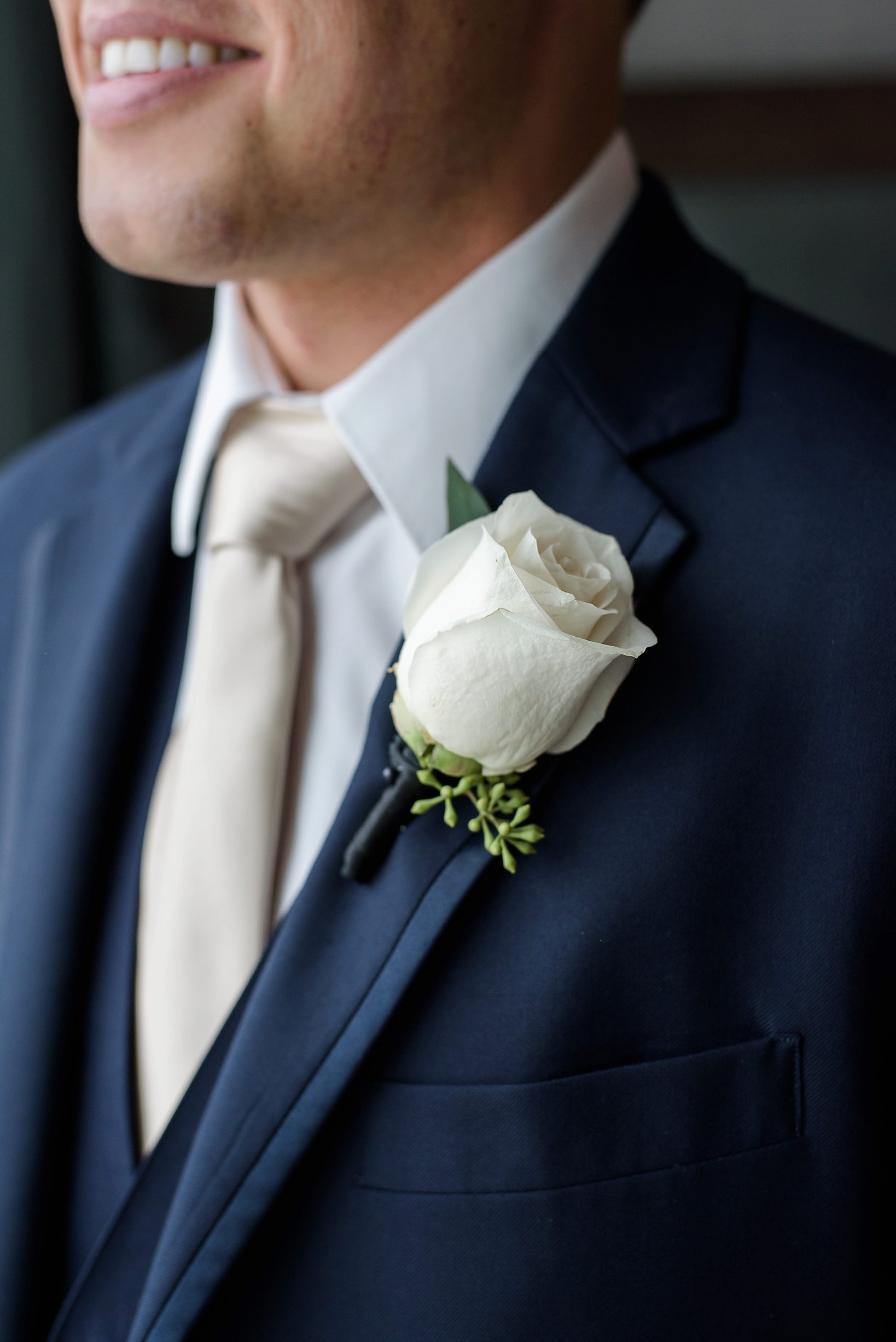 The groom's boutonniere of a white rose against his navy suit looked great 