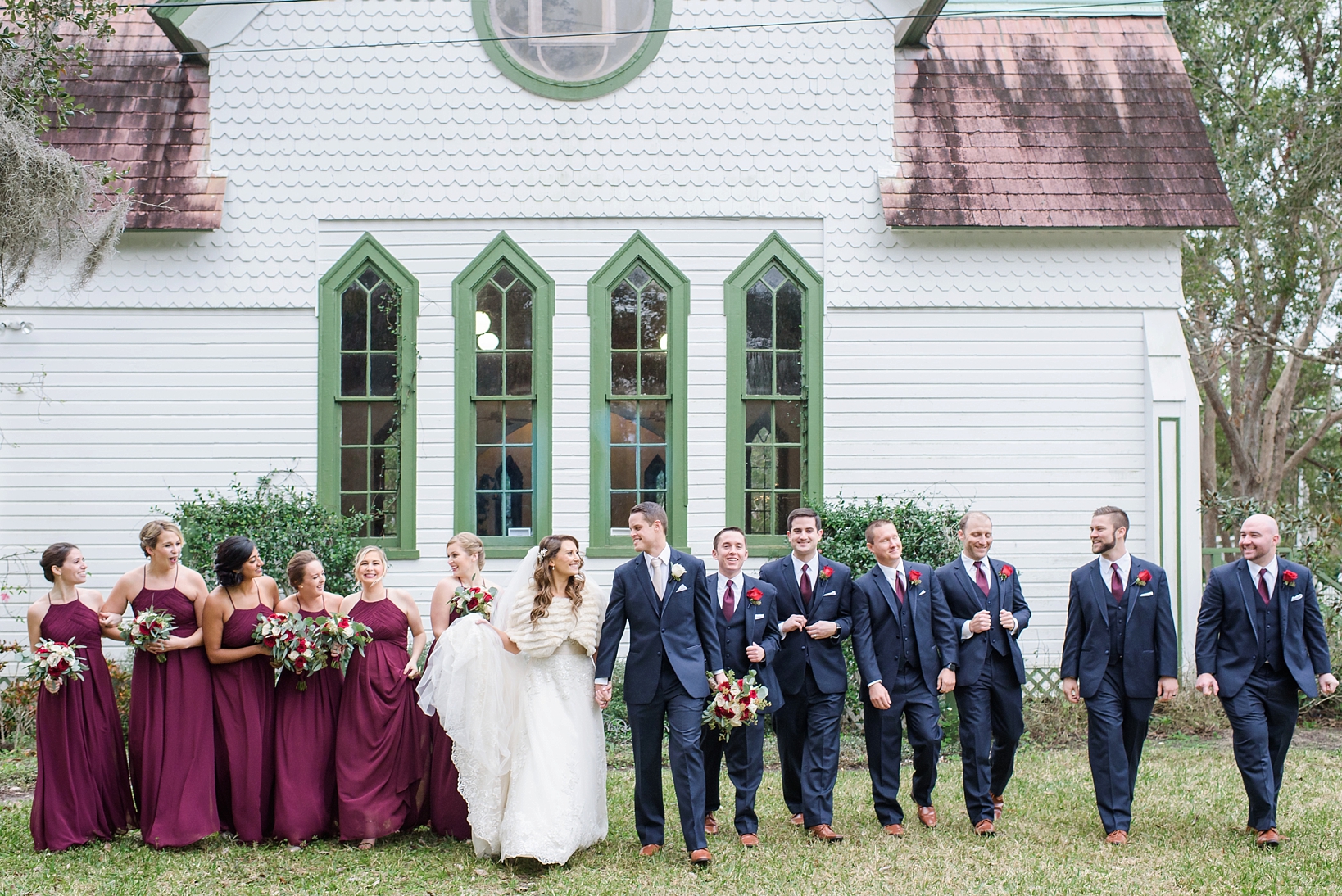 The bridal party in merlot and navy walking outside of the andrews memorial chapel in Dunedin, Florida