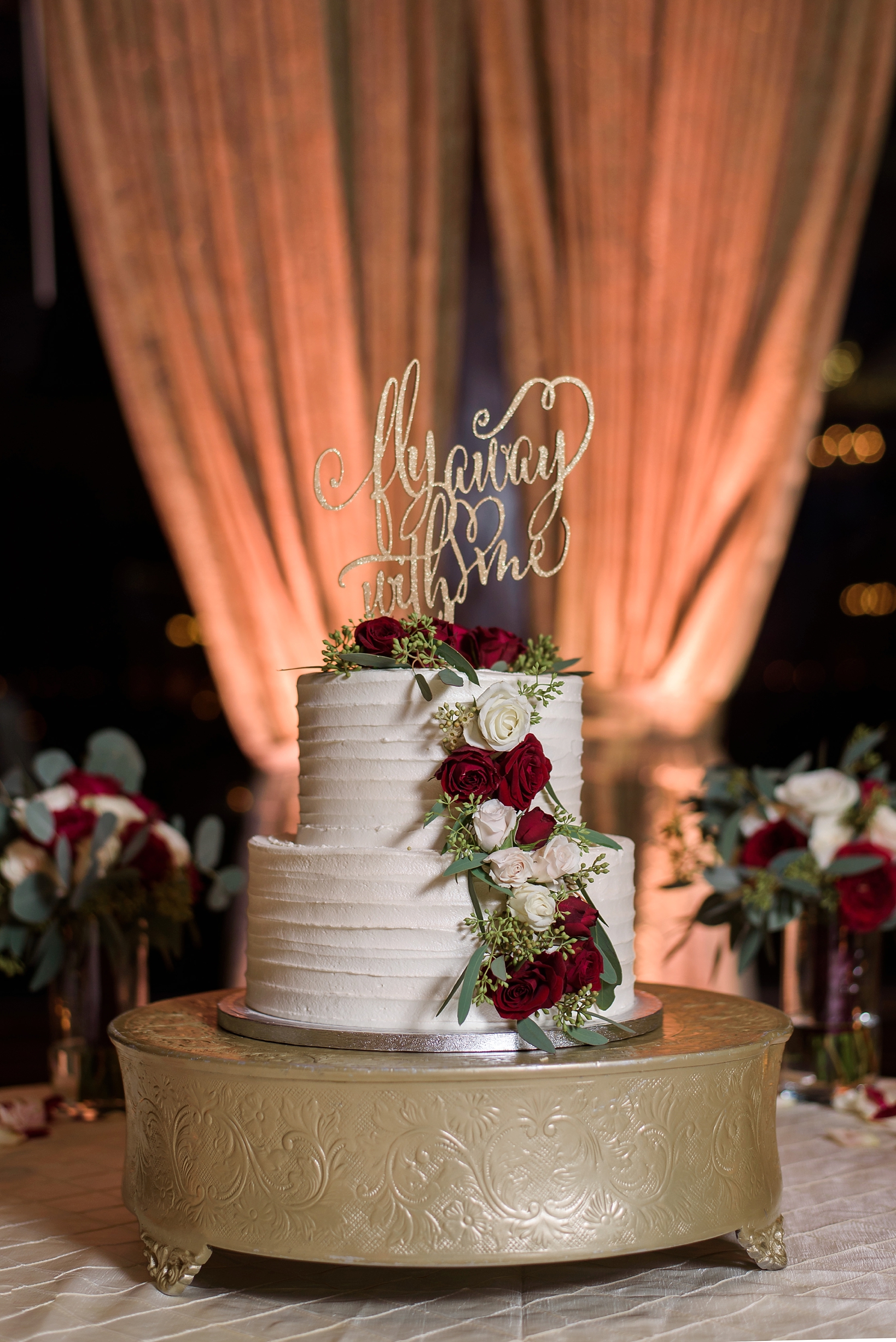The beautiful wedding cake with topper that says, "Fly away with me"