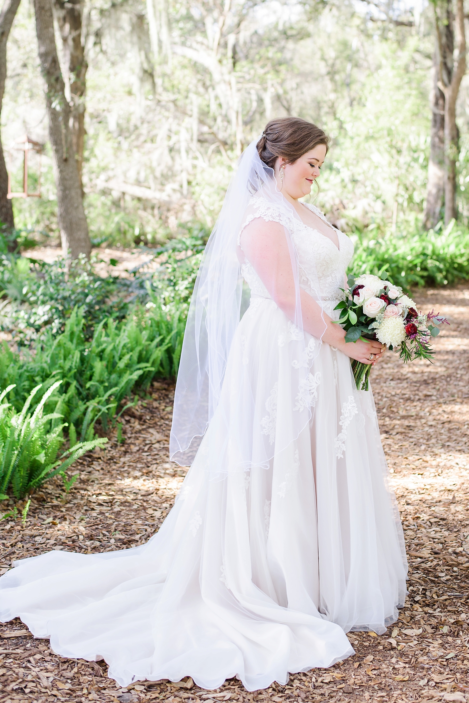 Classic image of a bride holding her flowers while standing in a rustic forest in Tampa Florida
