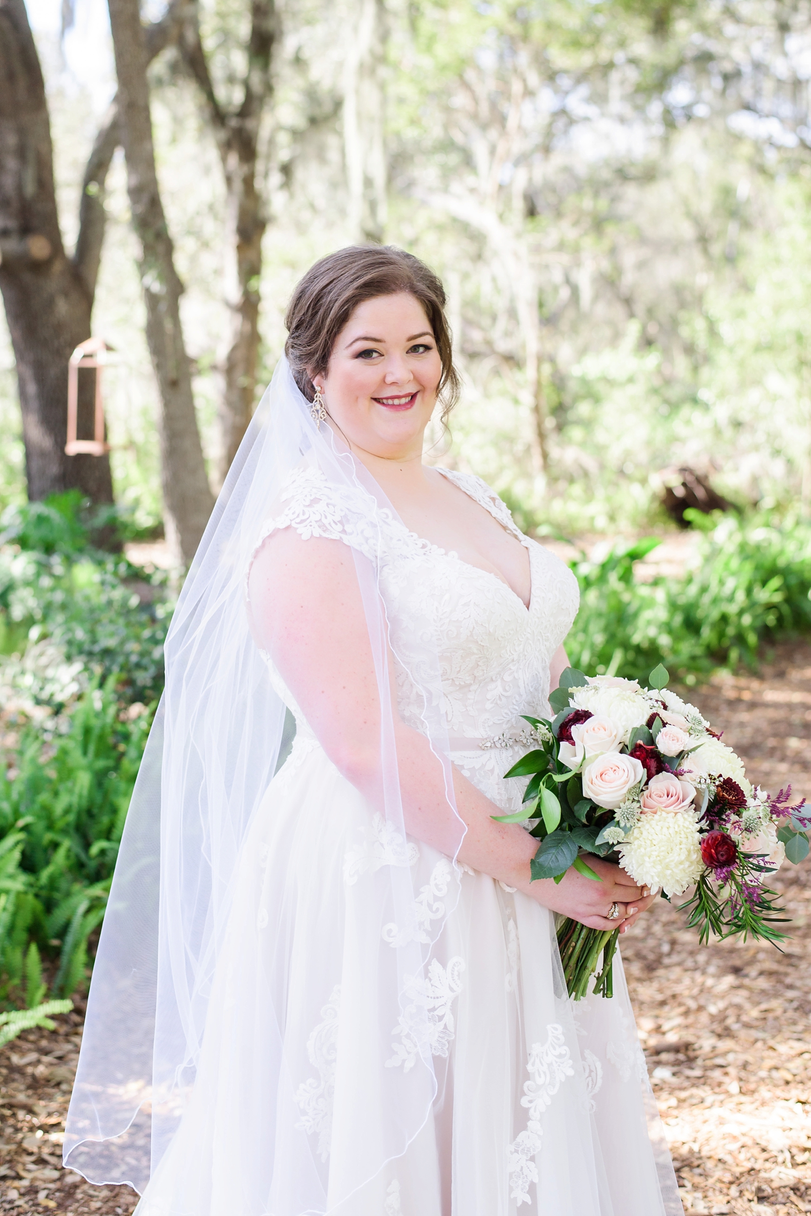 Bride holding her bouquet surrounded by natural light pouring in through the forest