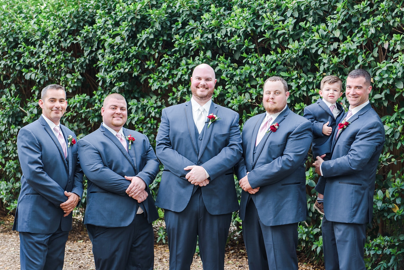 Groom and Groomsmen wearing Navy suits with red floral boutonniere 