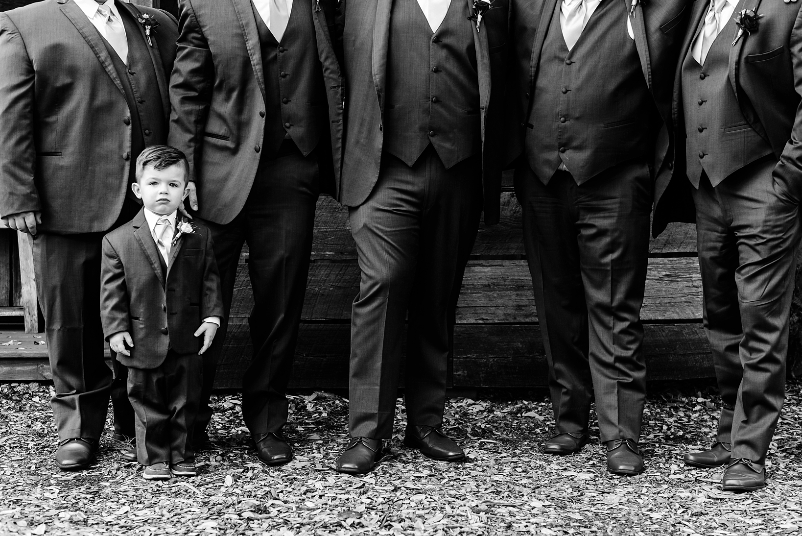 Ring bearer dwarfed by all the tall groomsmen in classic black and white