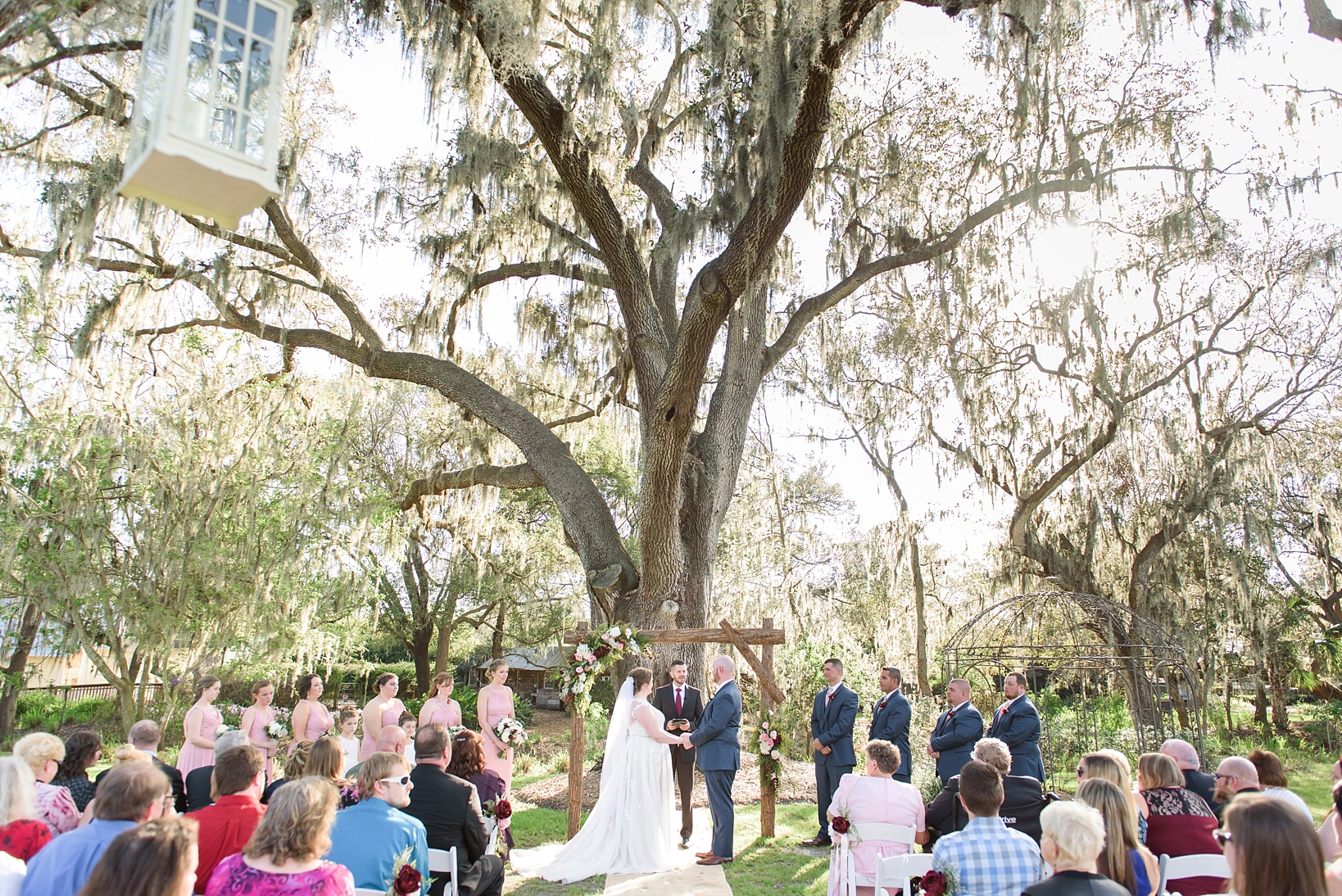 The bride and groom standing at the altar under the oak tree at cross creek ranch by Sarah & Ben Photography