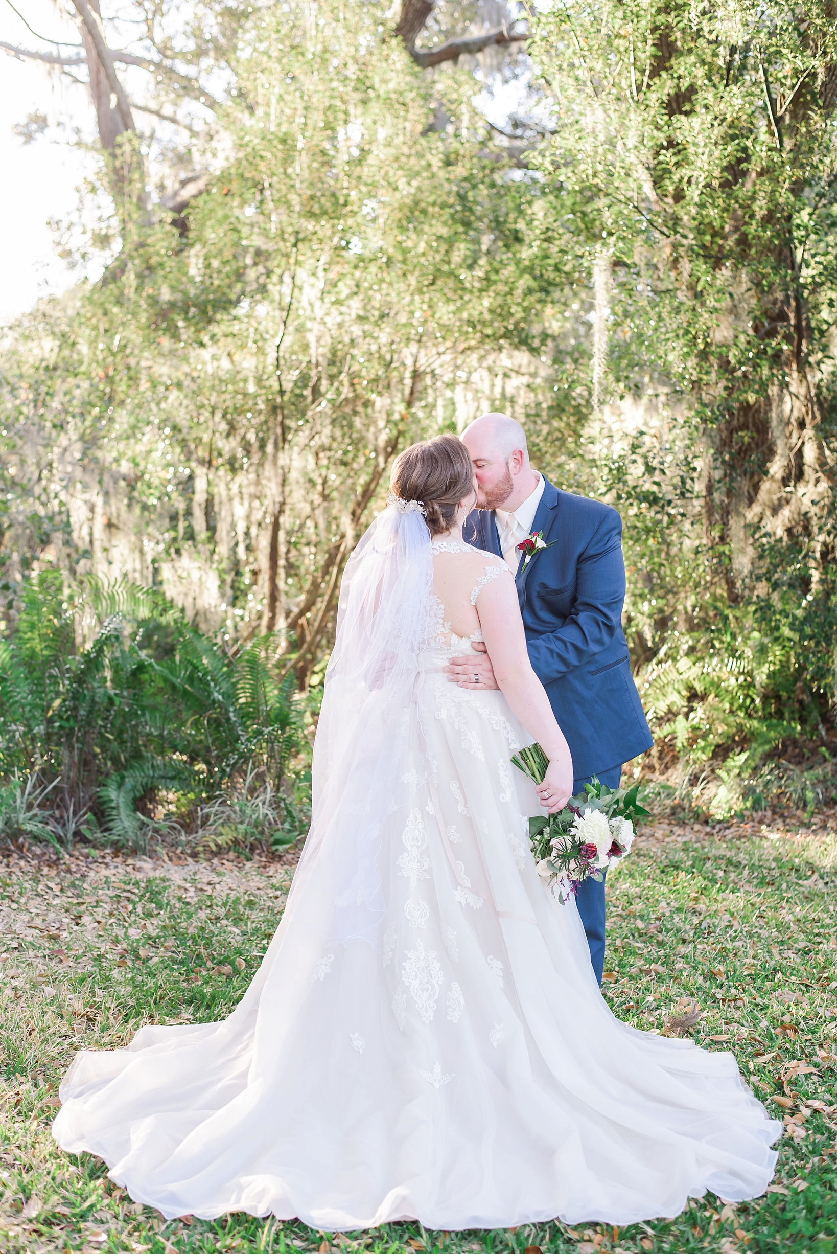 Flowing wedding gown on the bride as they share a kiss in the rustic forests of Seffner, FL