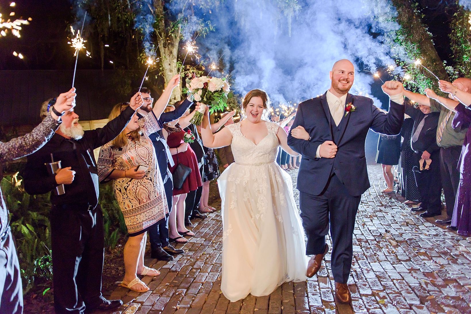 Bride and Groom running through a tunnel of sparklers by Sarah & Ben Photography