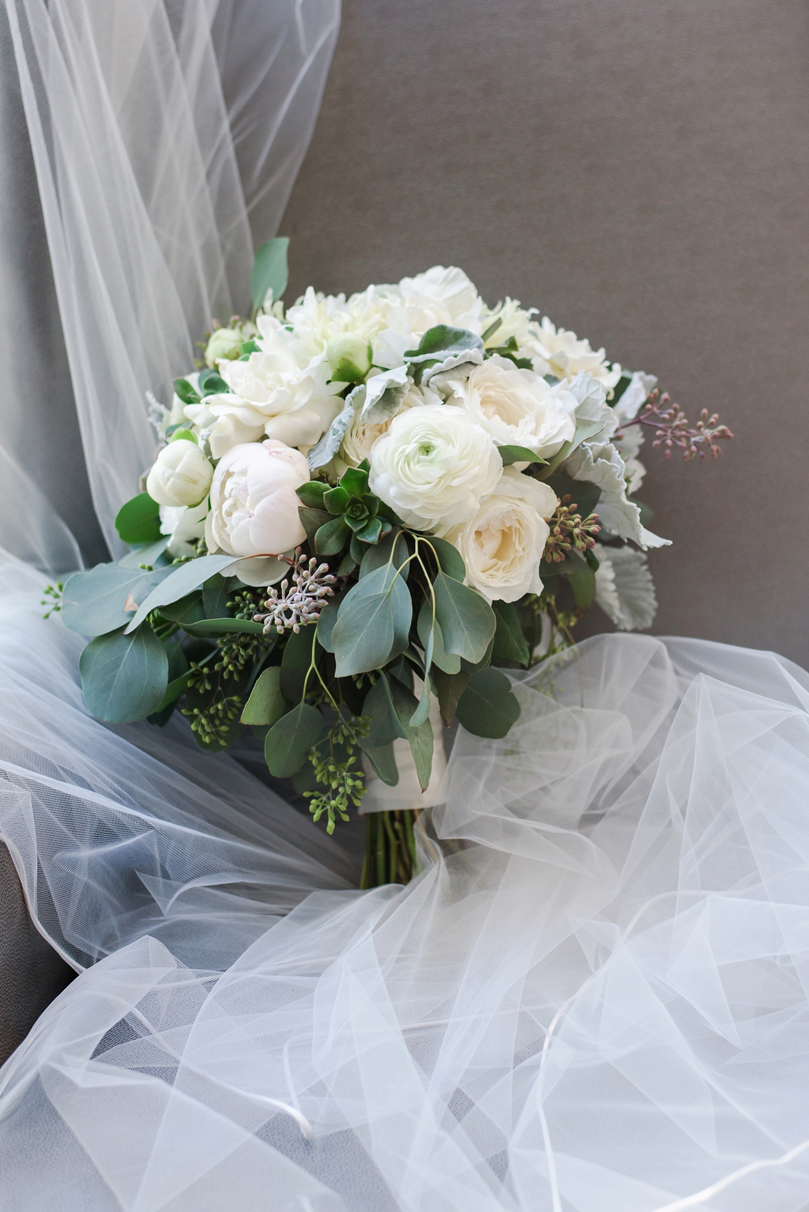The bridal bouquet surrounded by the brides cathedral veil 