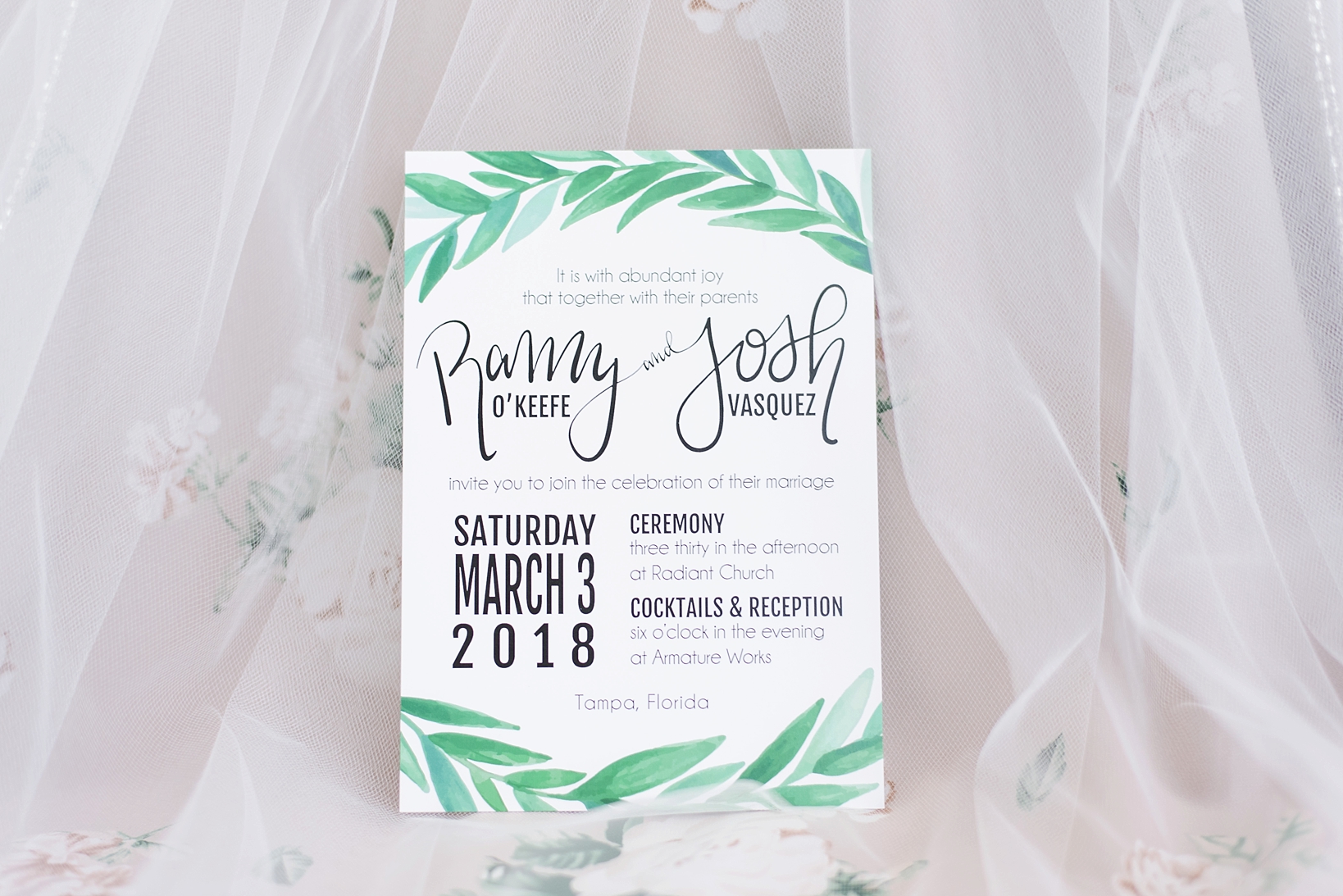 Wedding invitation with fern accents against a floral tulle skirt