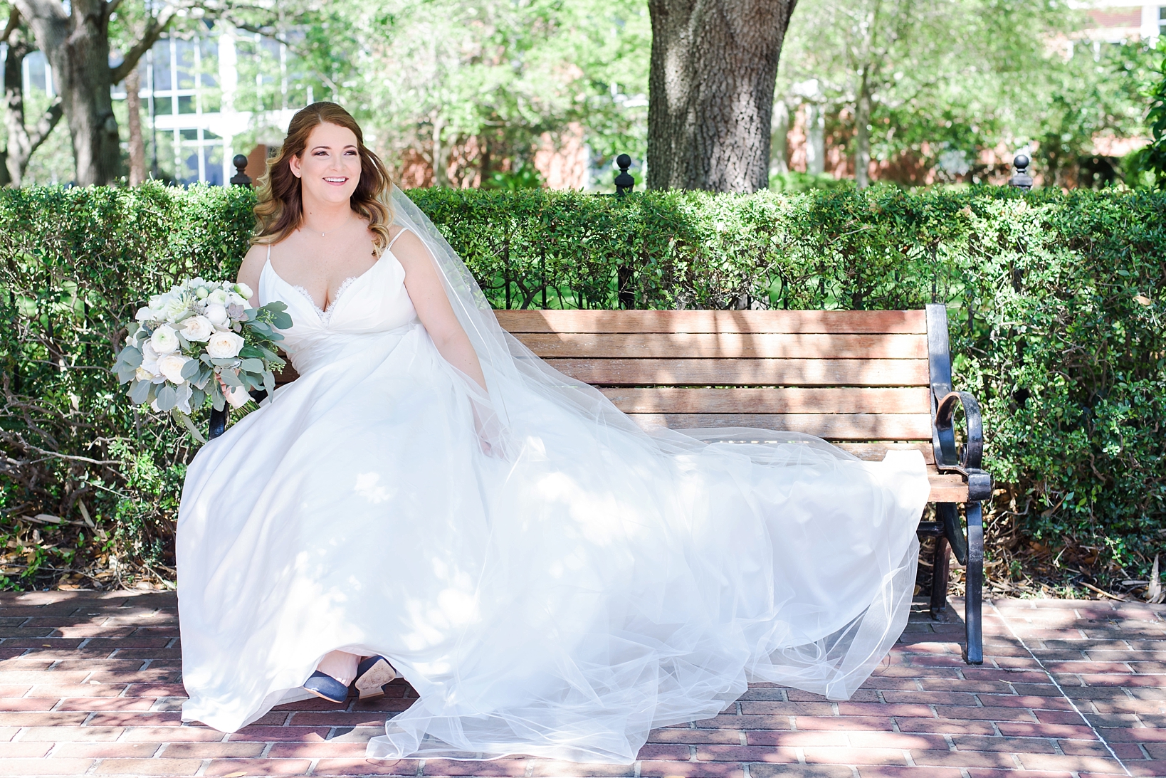 Bride kicking back on a park bench with her floral bouquet by Sarah & Ben Photography