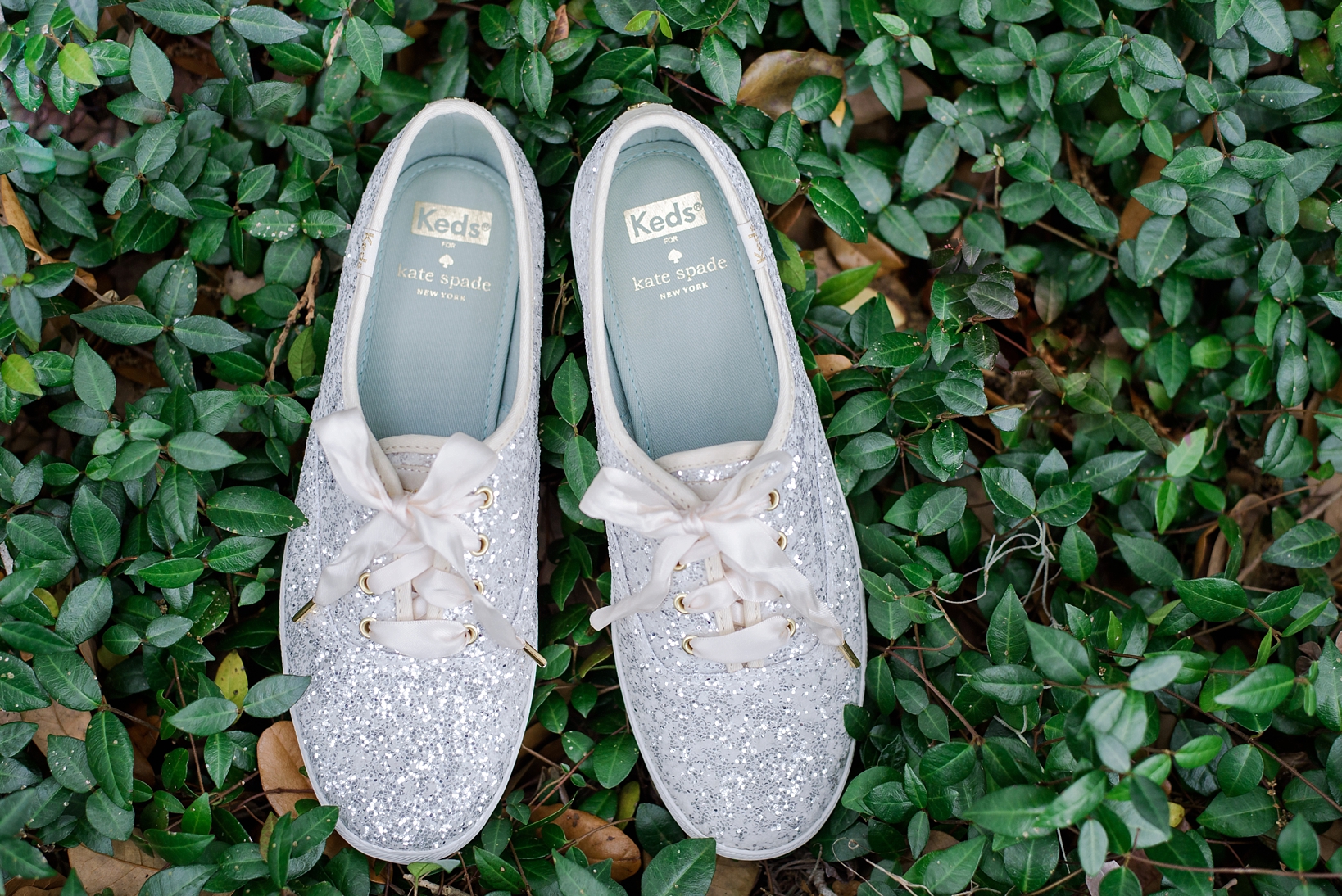 White Kate Spade Keds sneakers on a bed of rustic florals ready for dancing at the cross creek ranch reception photographed y Sarah and Ben Photography