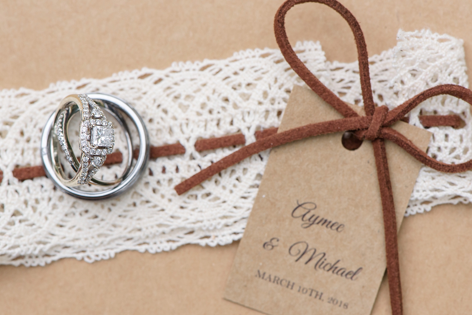 Wedding rings against white lace and leather string of the invite at a wedding in rural Tampa, FL